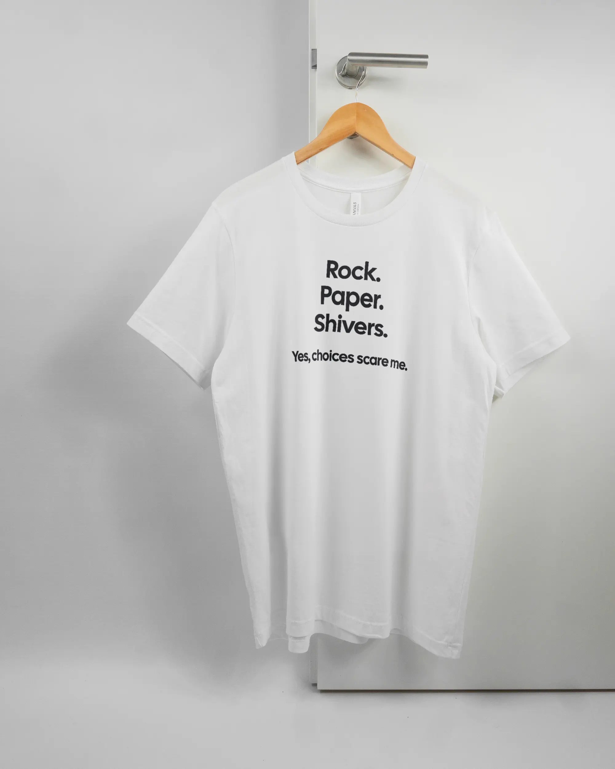 Vorderseite des Basic Unisex T-Shirt Light von Maondo mit dem Design Rock Paper Shivers in der Farbe White und in der Größe L auf einem Bügel an der Türklinke aufgehängt