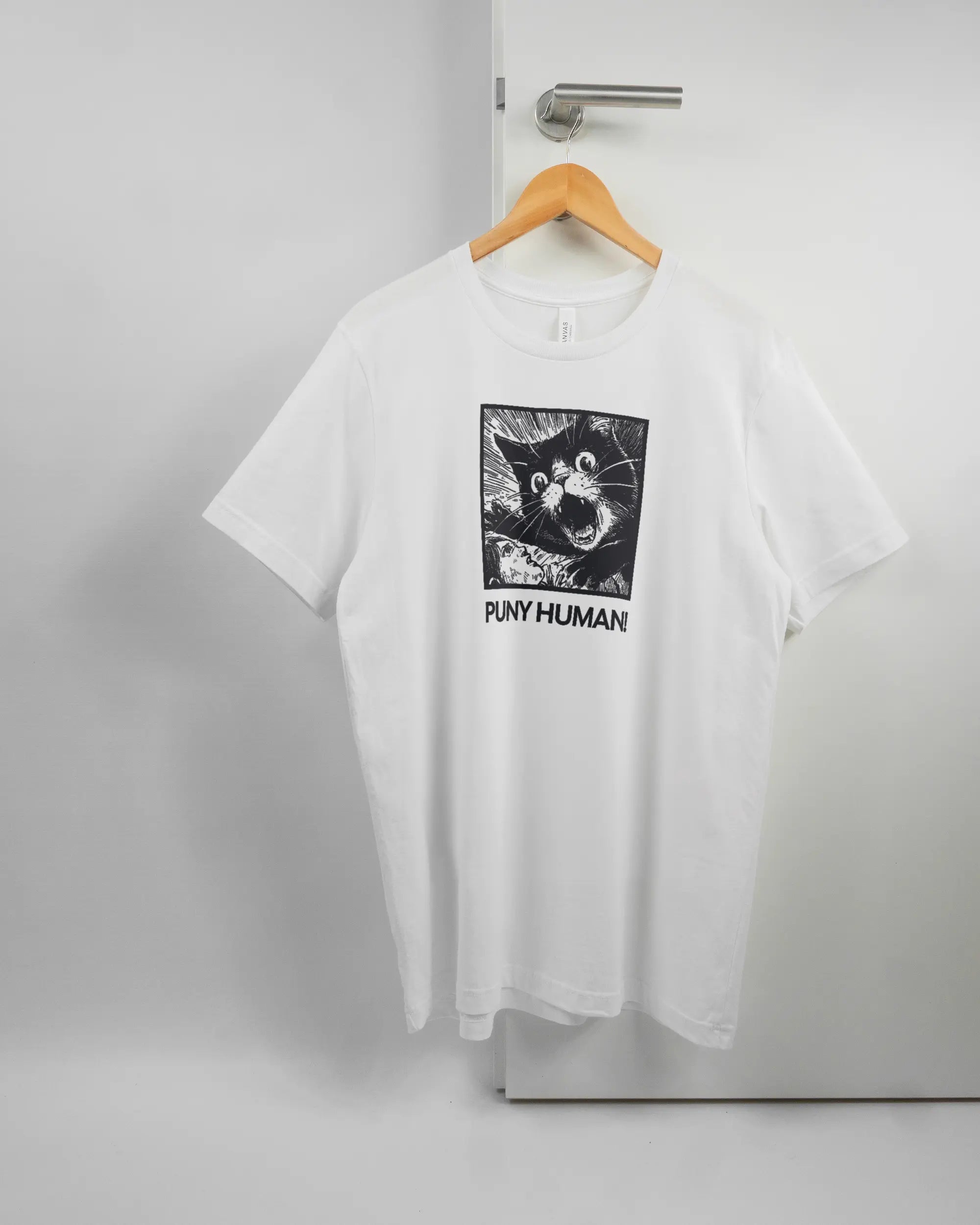 Vorderseite des Basic Unisex T-Shirt Light von Maondo mit dem Design Puny Human in der Farbe White und in der Größe L auf einem Bügel an der Türklinke aufgehängt