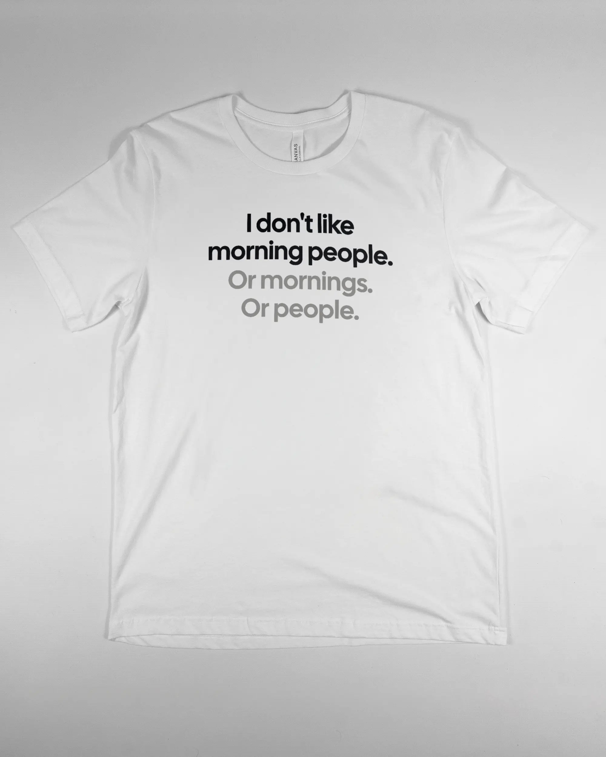 Vorderseite des Basic Unisex T-Shirt Light von Maondo mit dem Design Morning Person in der Farbe White und in der Größe L flach auf den Boden gelegt