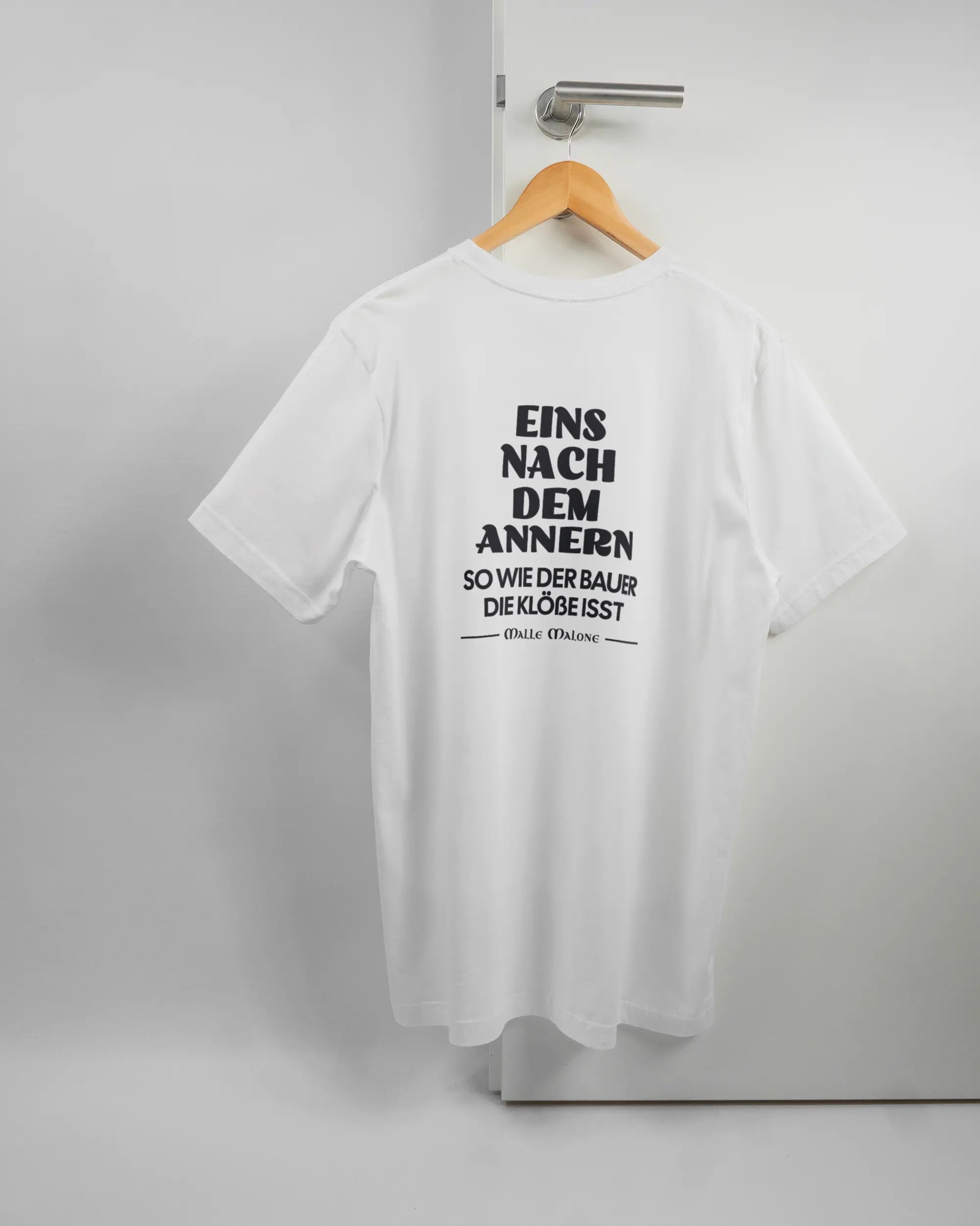 Rückseite des Basic Unisex T-Shirt Light von Maondo mit dem Design Eins nach dem Annern in der Farbe White und in der Größe L auf einem Bügel an der Türklinke aufgehängt
