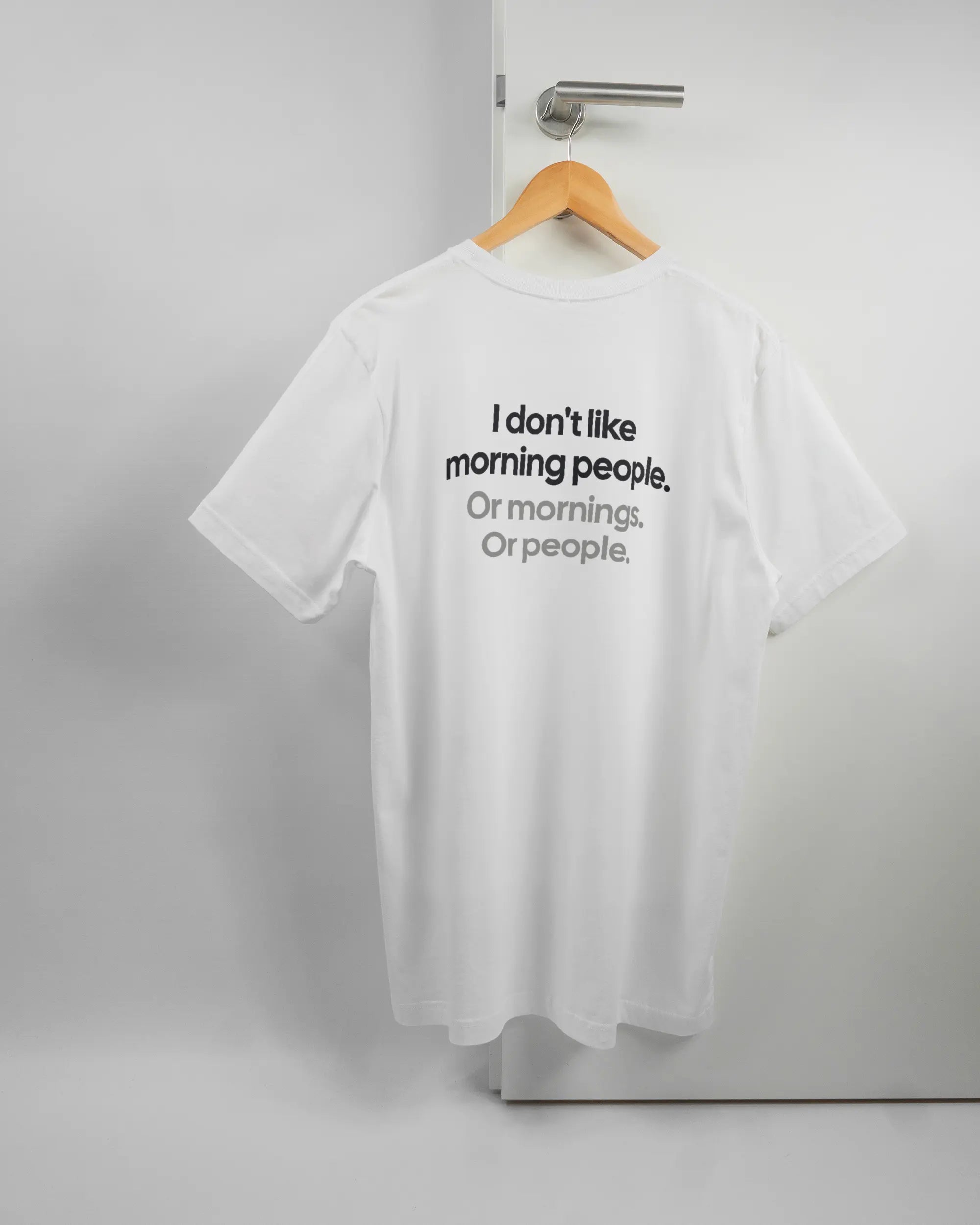Rückseite des Basic Unisex T-Shirt Light von Maondo mit dem Design Morning Person in der Farbe White und in der Größe L auf einem Bügel an der Türklinke aufgehängt