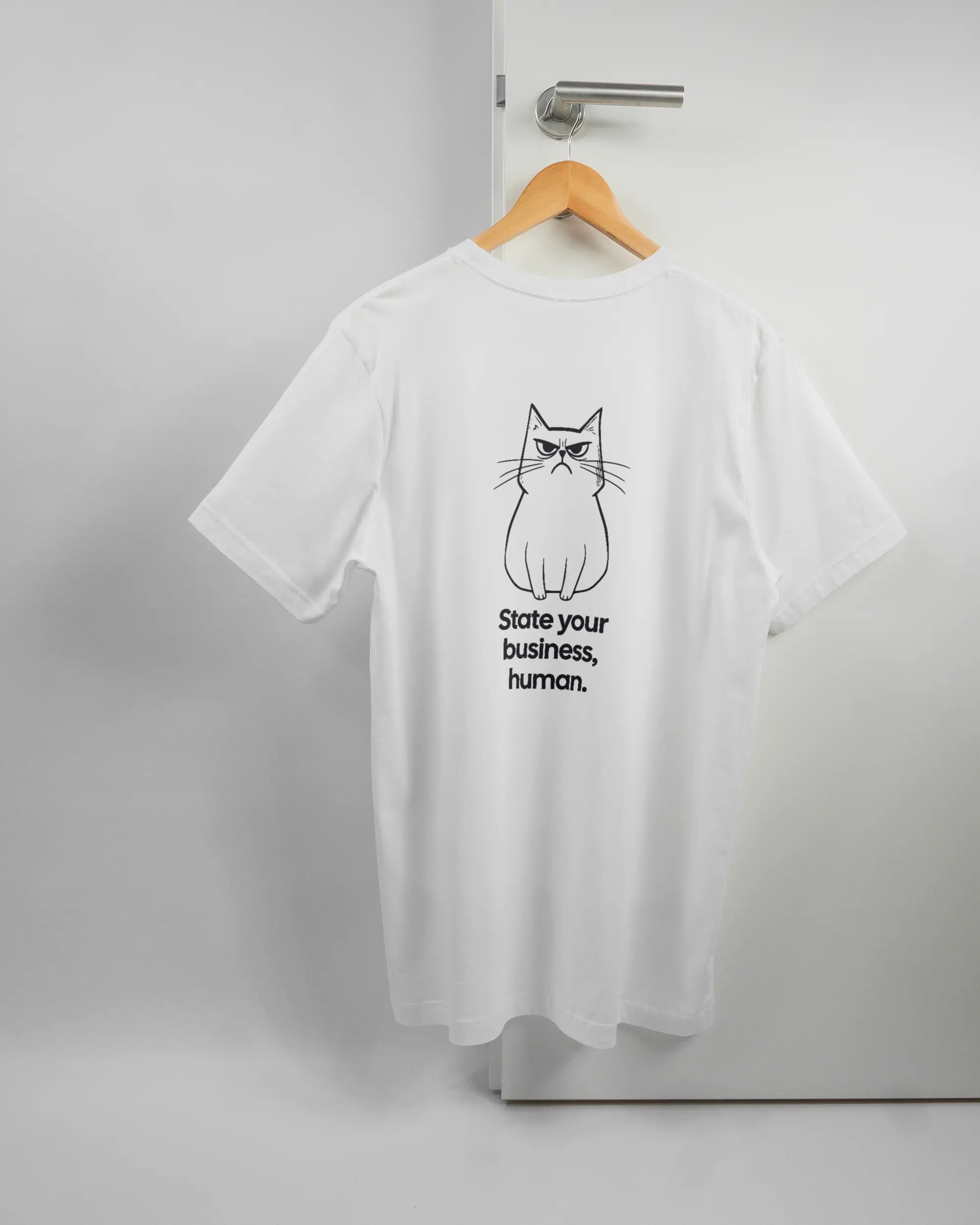 Rückseite des Basic Unisex T-Shirt Light von Maondo mit dem Design Grumpy Purr in der Farbe White und in der Größe L auf einem Bügel an der Türklinke aufgehängt