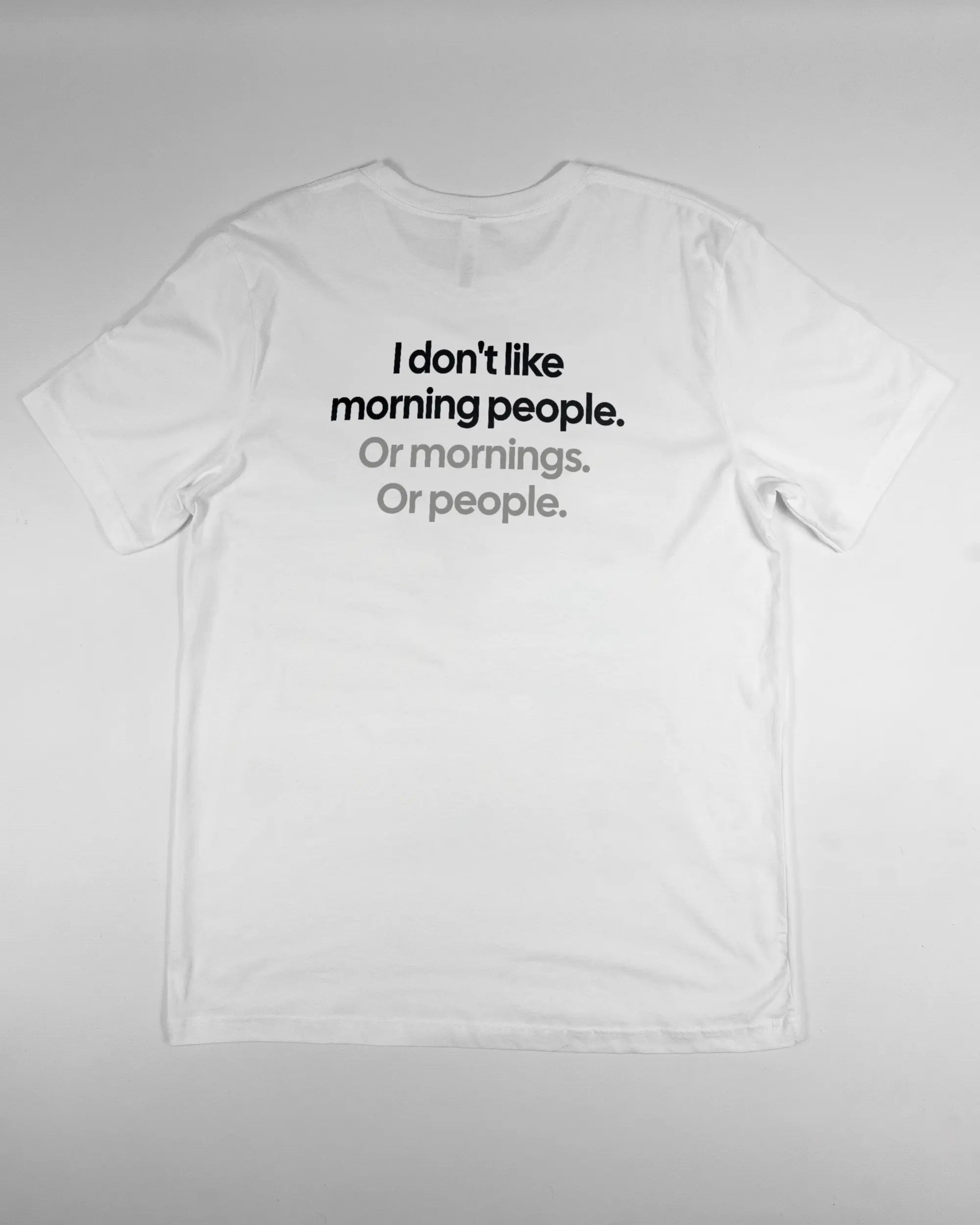 Rückseite des Basic Unisex T-Shirt Light von Maondo mit dem Design Morning Person in der Farbe White und in der Größe L flach auf den Boden gelegt