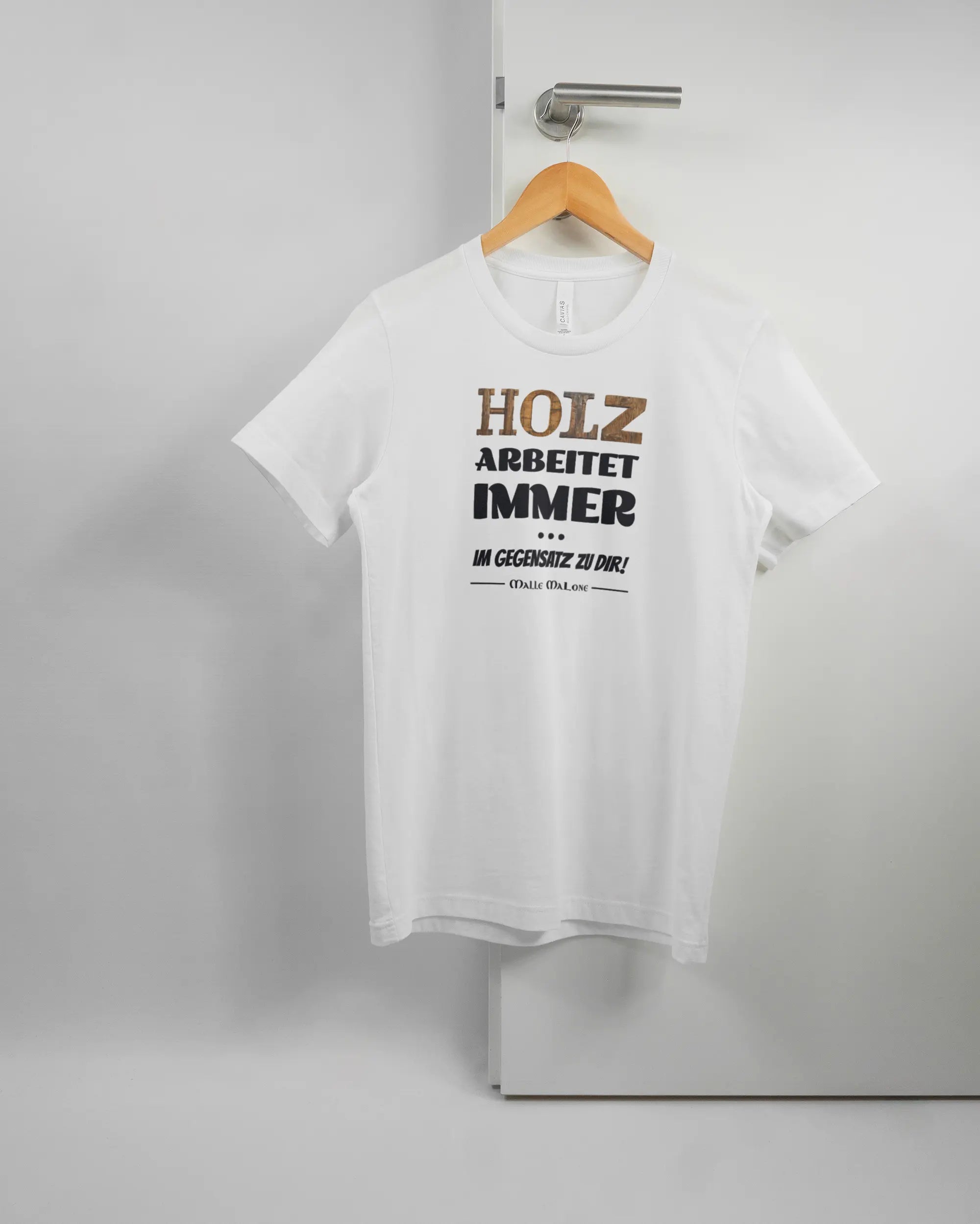 Vorderseite des Basic Unisex T-Shirt Light von Maondo mit dem Design Holzarbeit in der Farbe White und in der Größe S auf einem Bügel an der Türklinke aufgehängt