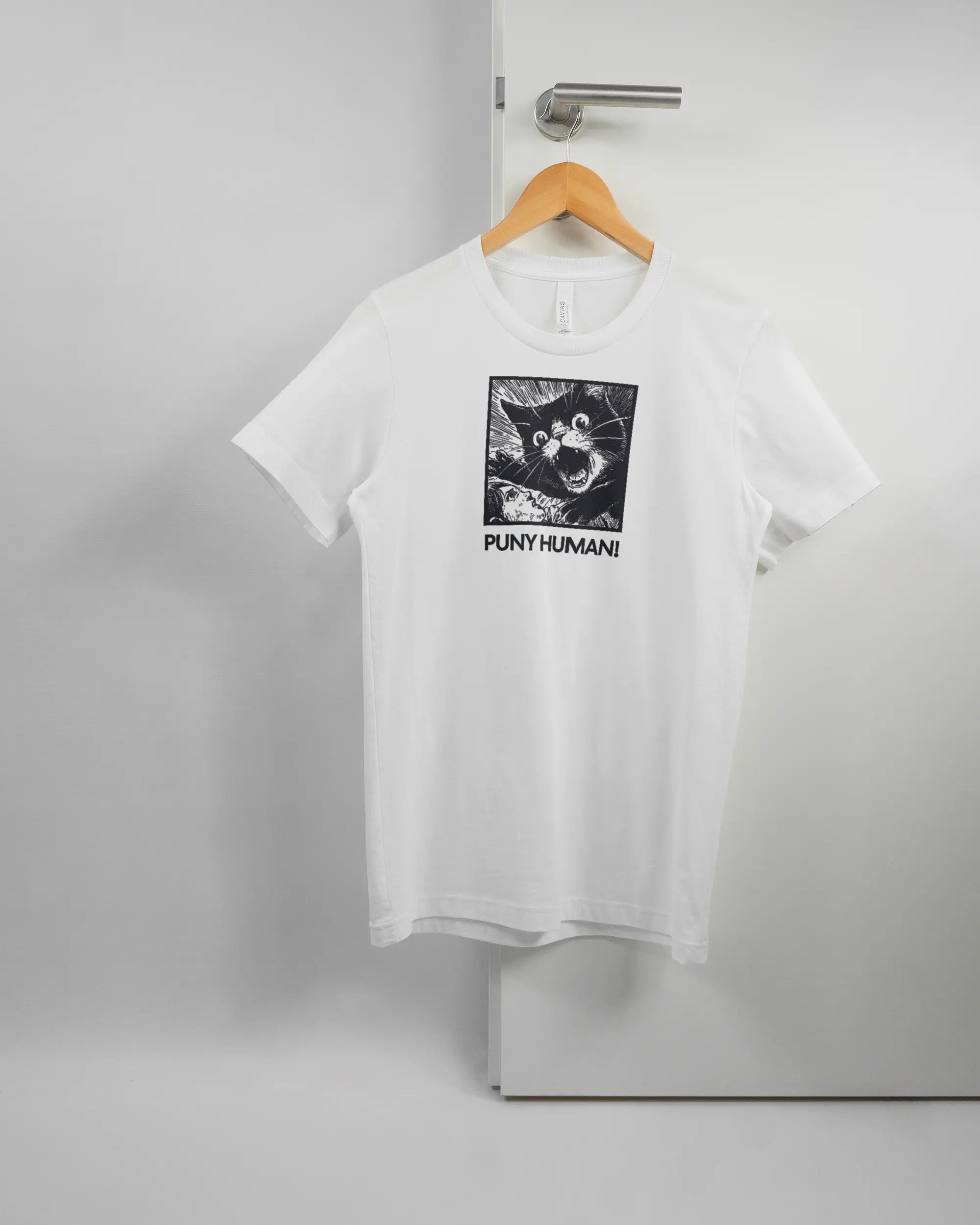Vorderseite des Basic Unisex T-Shirt Light von Maondo mit dem Design Puny Human in der Farbe White und in der Größe S auf einem Bügel an der Türklinke aufgehängt