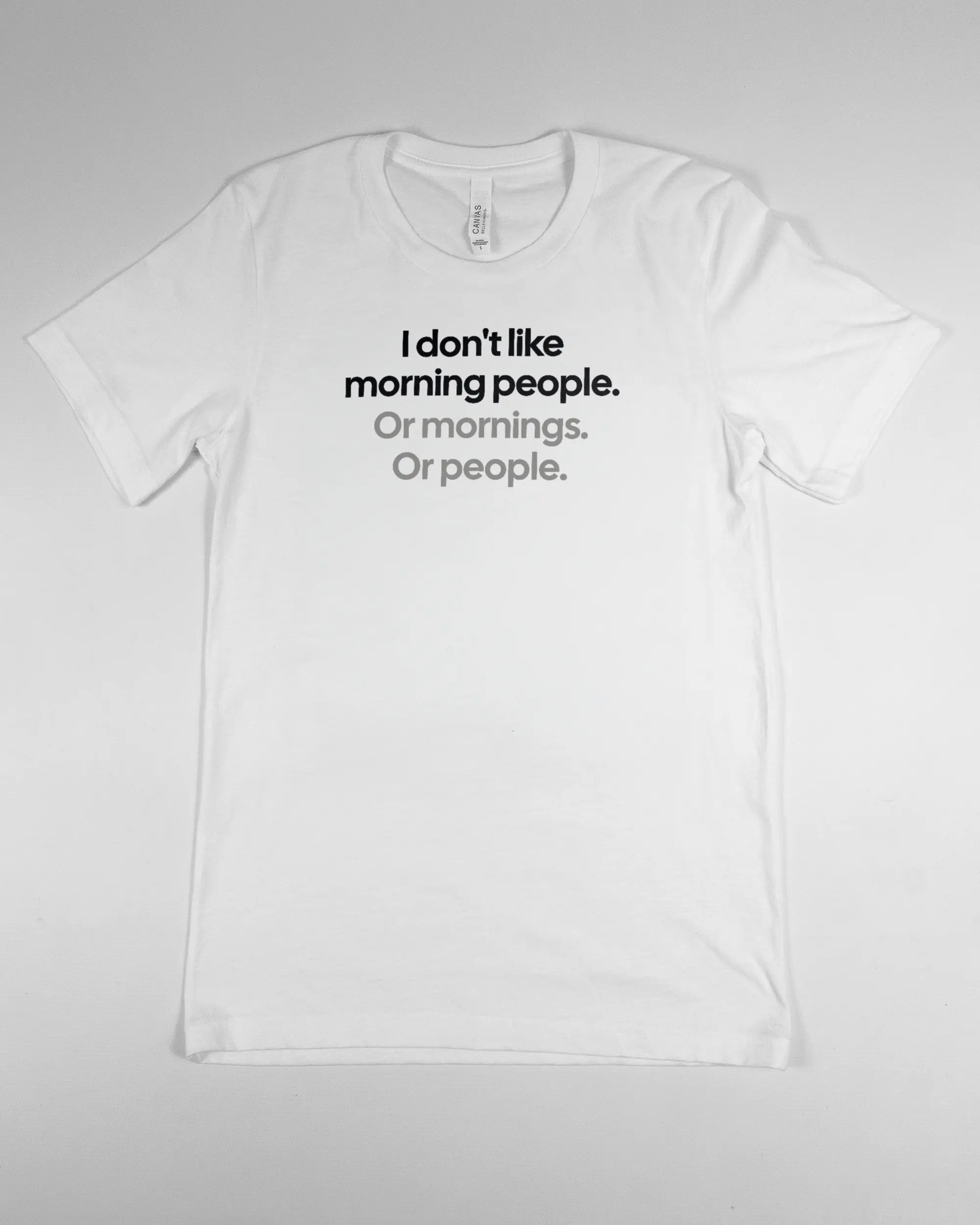 Vorderseite des Basic Unisex T-Shirt Light von Maondo mit dem Design Morning Person in der Farbe White und in der Größe S flach auf den Boden gelegt