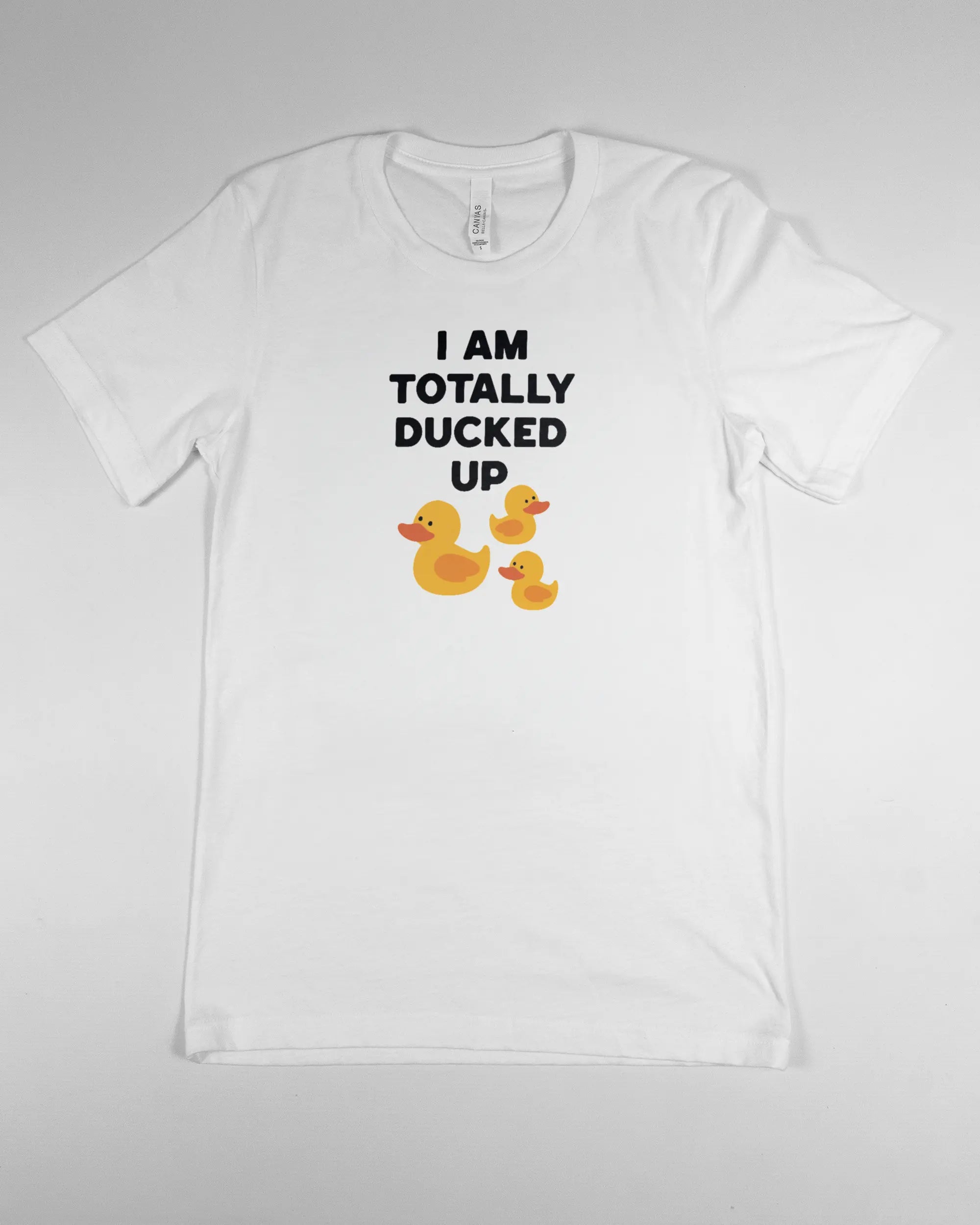 Vorderseite des Basic Unisex T-Shirt Light von Maondo mit dem Design Ducked Up in der Farbe White und in der Größe S flach auf den Boden gelegt