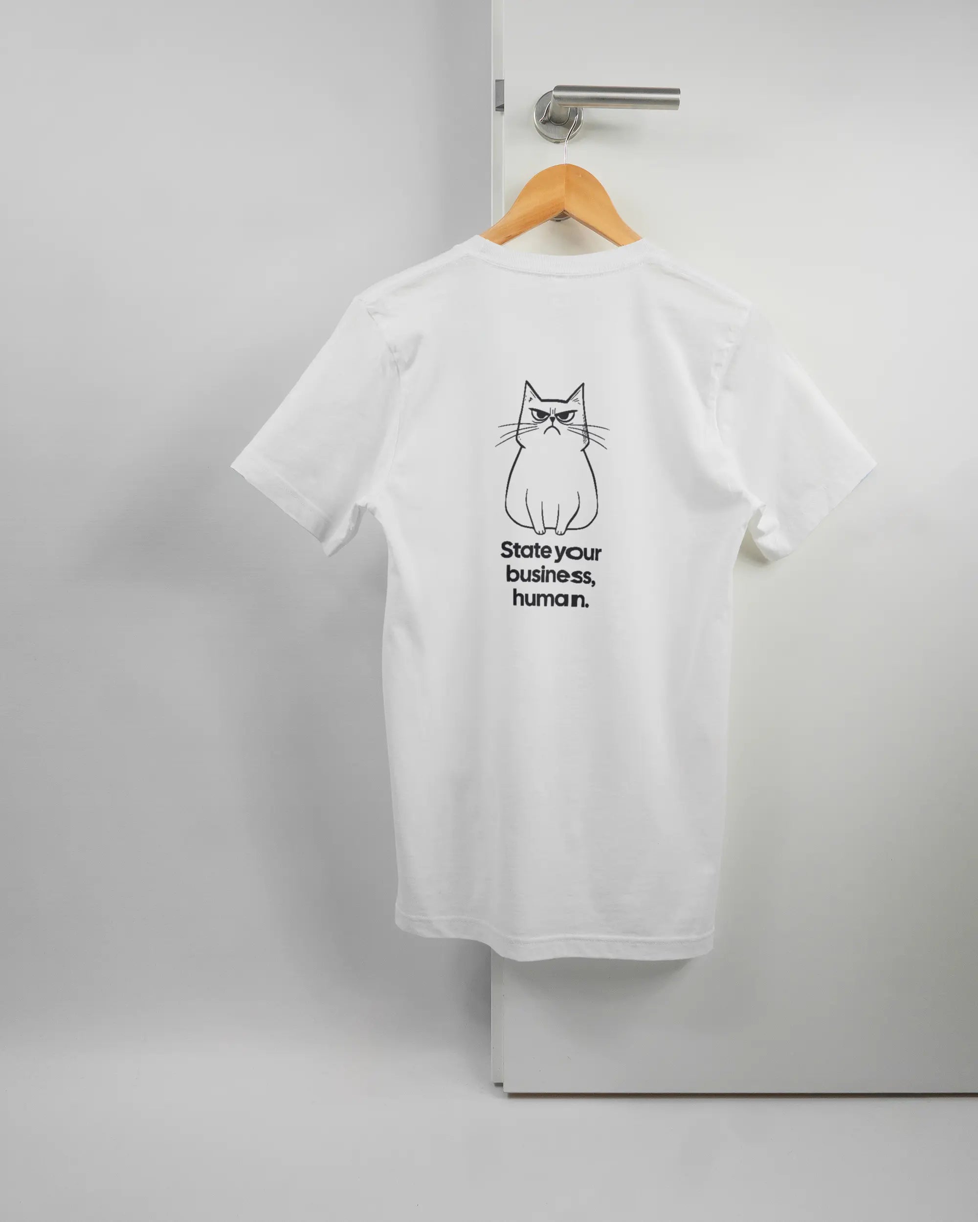 Rückseite des Basic Unisex T-Shirt Light von Maondo mit dem Design Grumpy Purr in der Farbe White und in der Größe S auf einem Bügel an der Türklinke aufgehängt