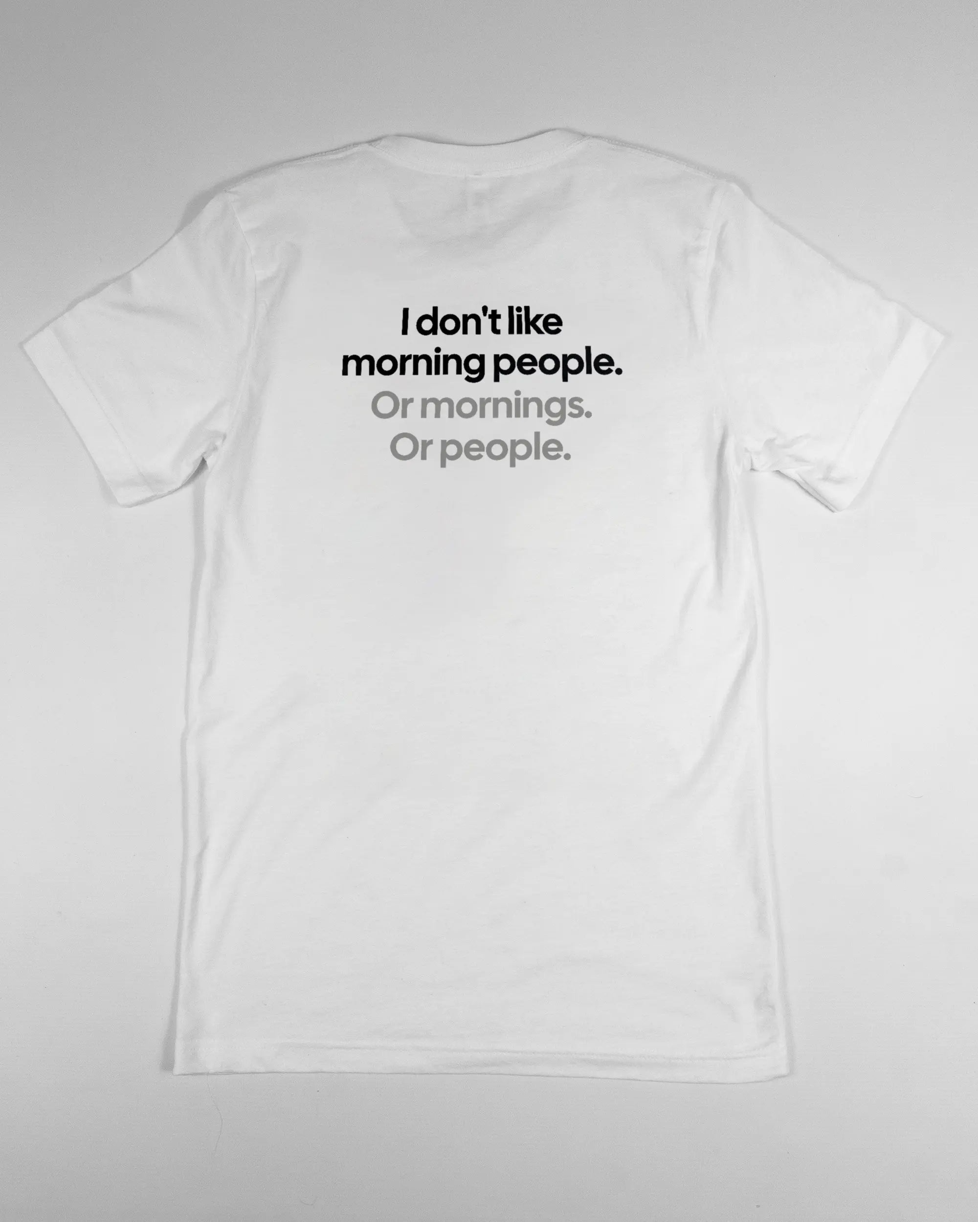 Rückseite des Basic Unisex T-Shirt Light von Maondo mit dem Design Morning Person in der Farbe White und in der Größe S flach auf den Boden gelegt