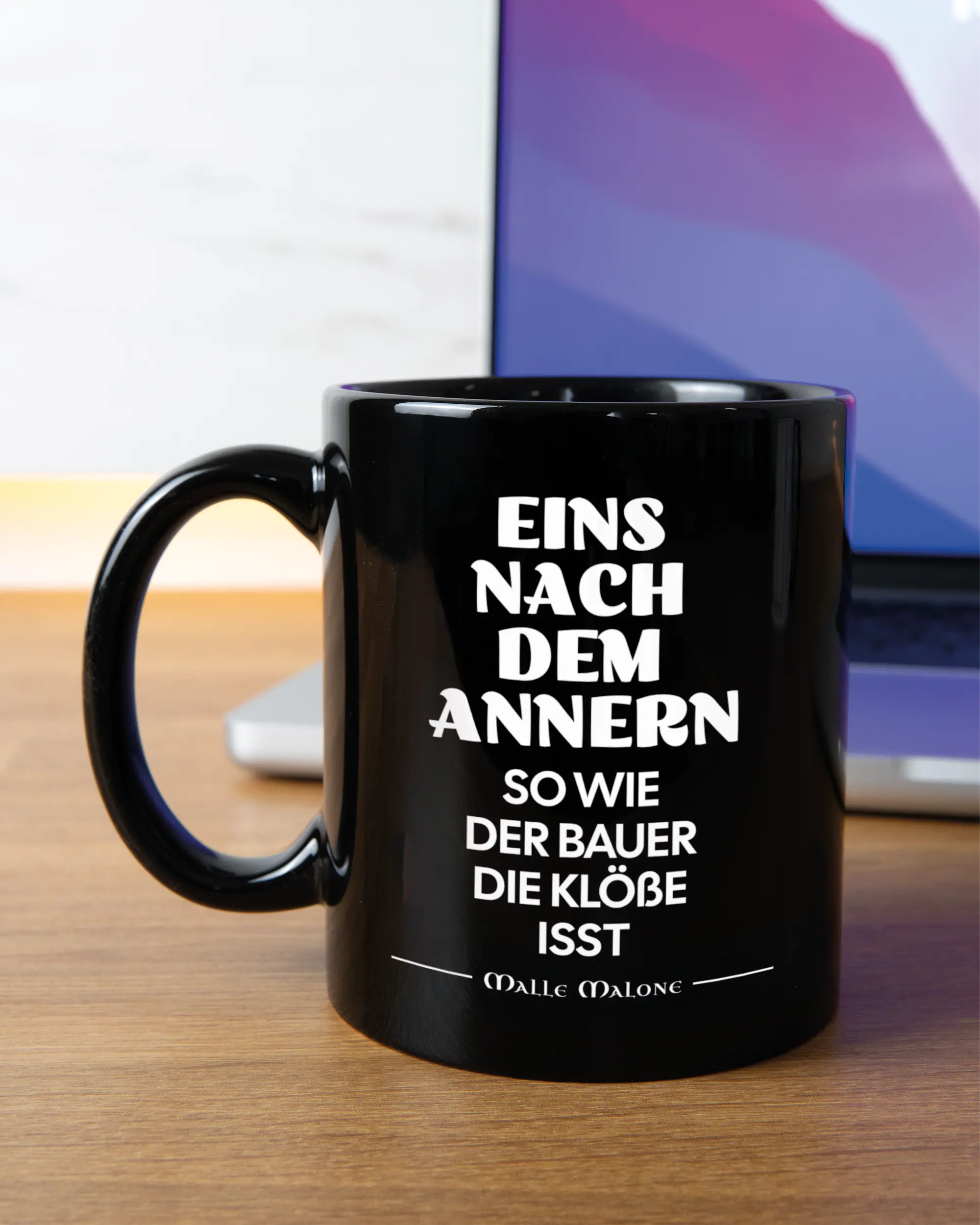 Homeoffice Aufnahme der linken Seite der beidseitig bedruckten Keramiktasse von Maondo mit dem Design Eins nach dem Annern in der Farbe Black