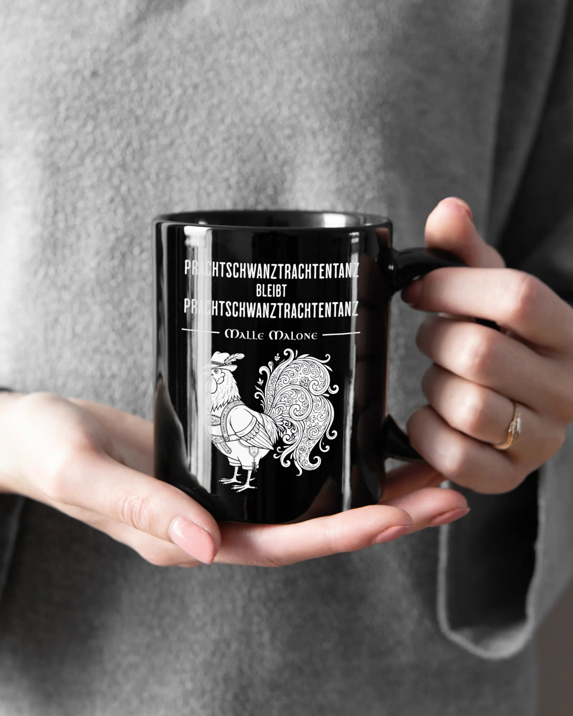 Rechte Seite der beidseitig bedruckten Keramiktasse von Maondo mit dem Design Trachtentanz in der Farbe Black gehalten von Frauenhänden