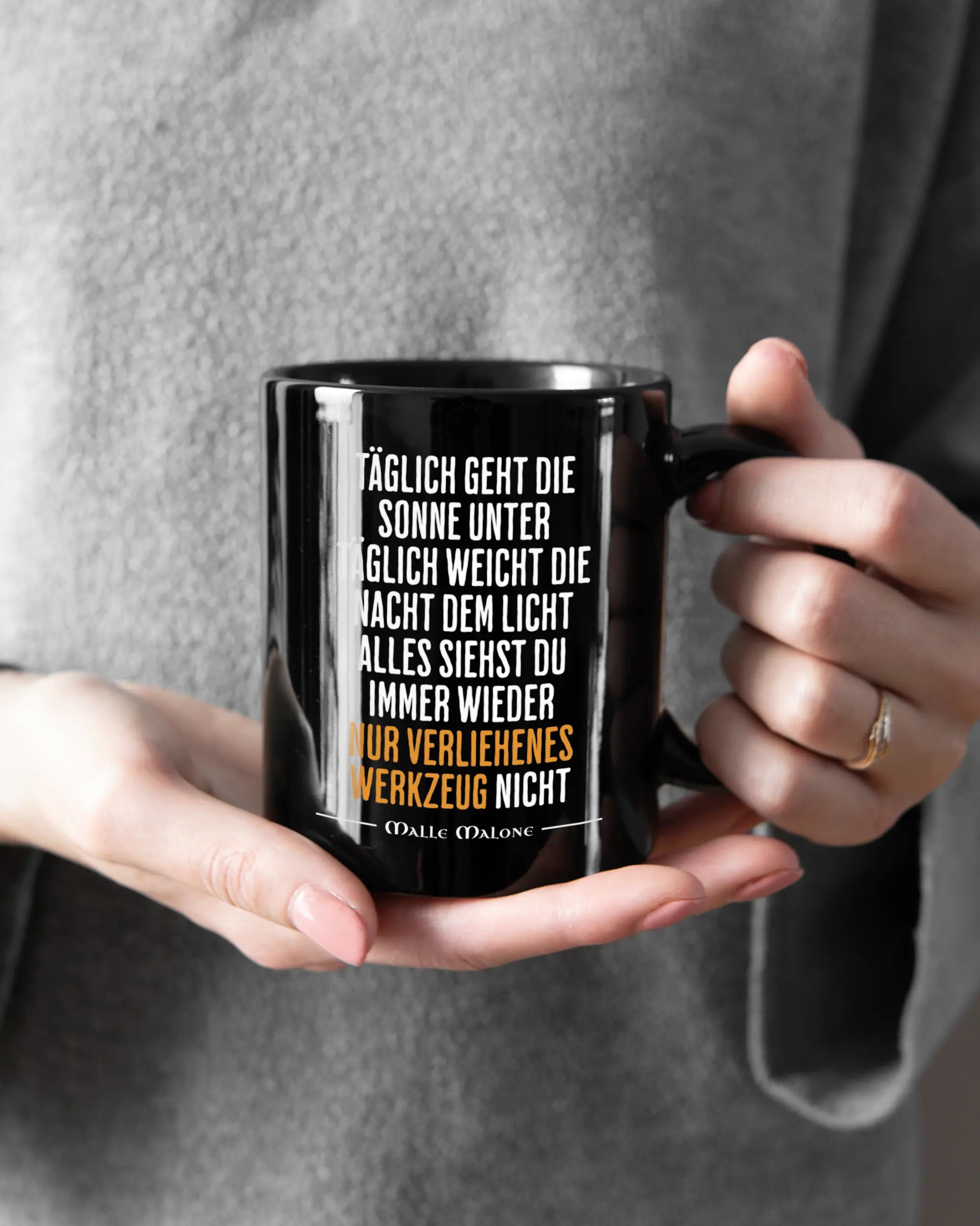 Rechte Seite der beidseitig bedruckten Keramiktasse von Maondo mit dem Design Wegzeug in der Farbe Black gehalten von Frauenhänden