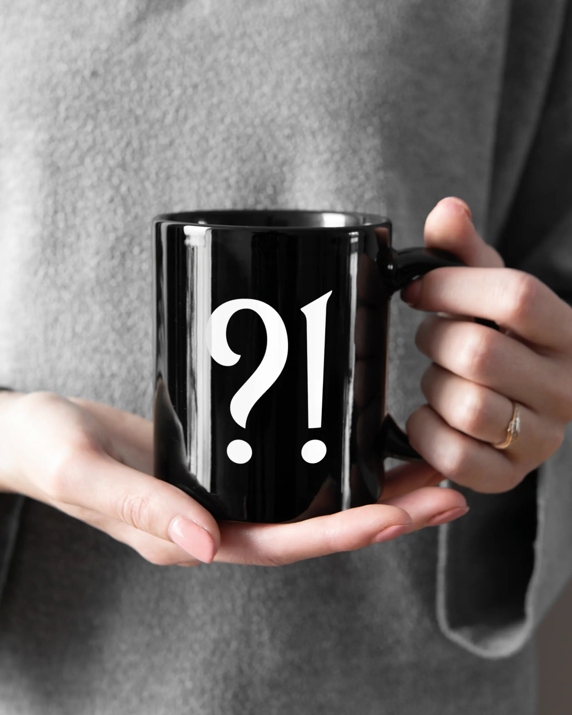 Rechte Seite der beidseitig bedruckten Keramiktasse von Maondo mit dem Design WHAT in der Farbe Black gehalten von Frauenhänden