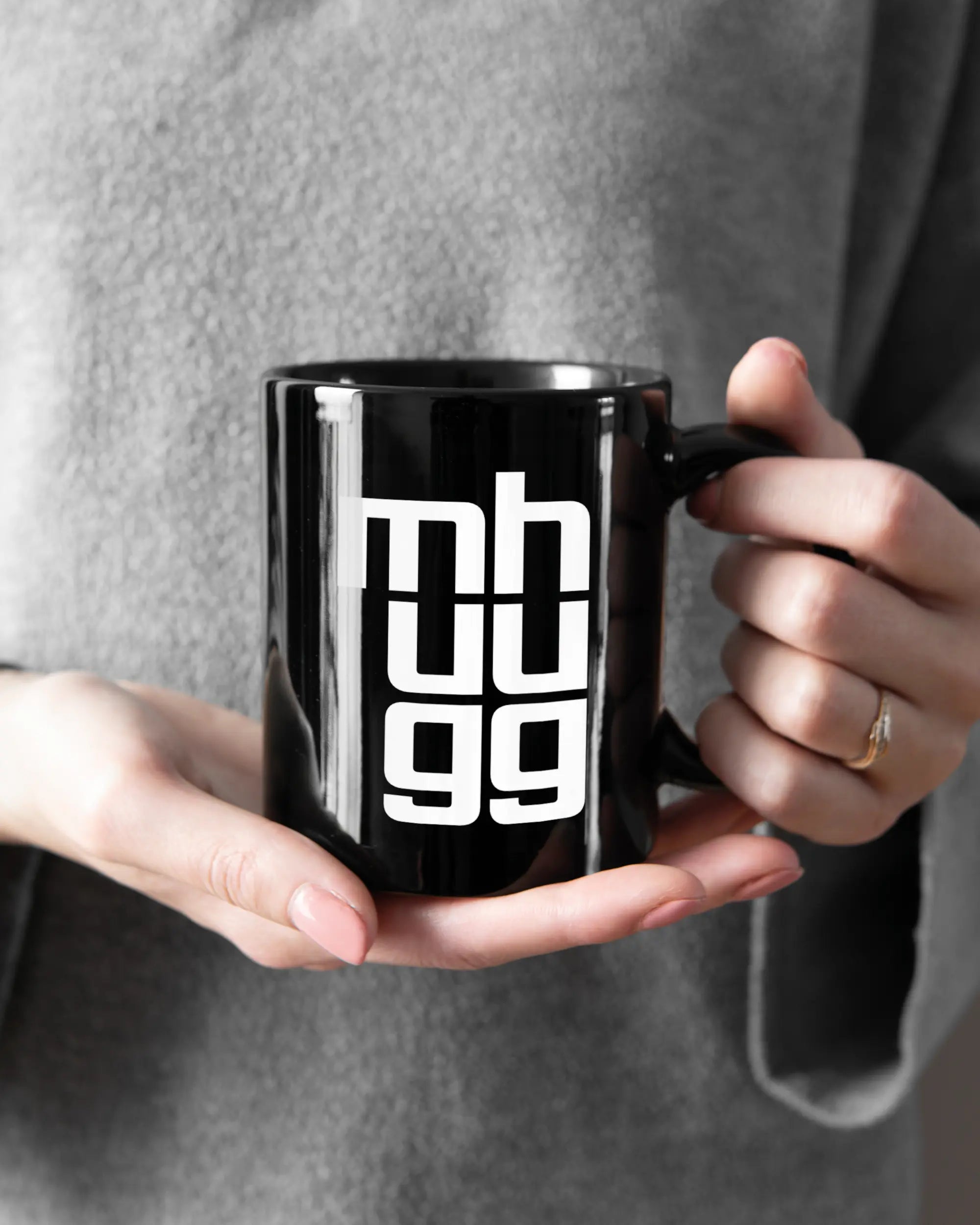 Rechte Seite der beidseitig bedruckten Keramiktasse von Maondo mit dem Design Hug Mug in der Farbe Black gehalten von Frauenhänden