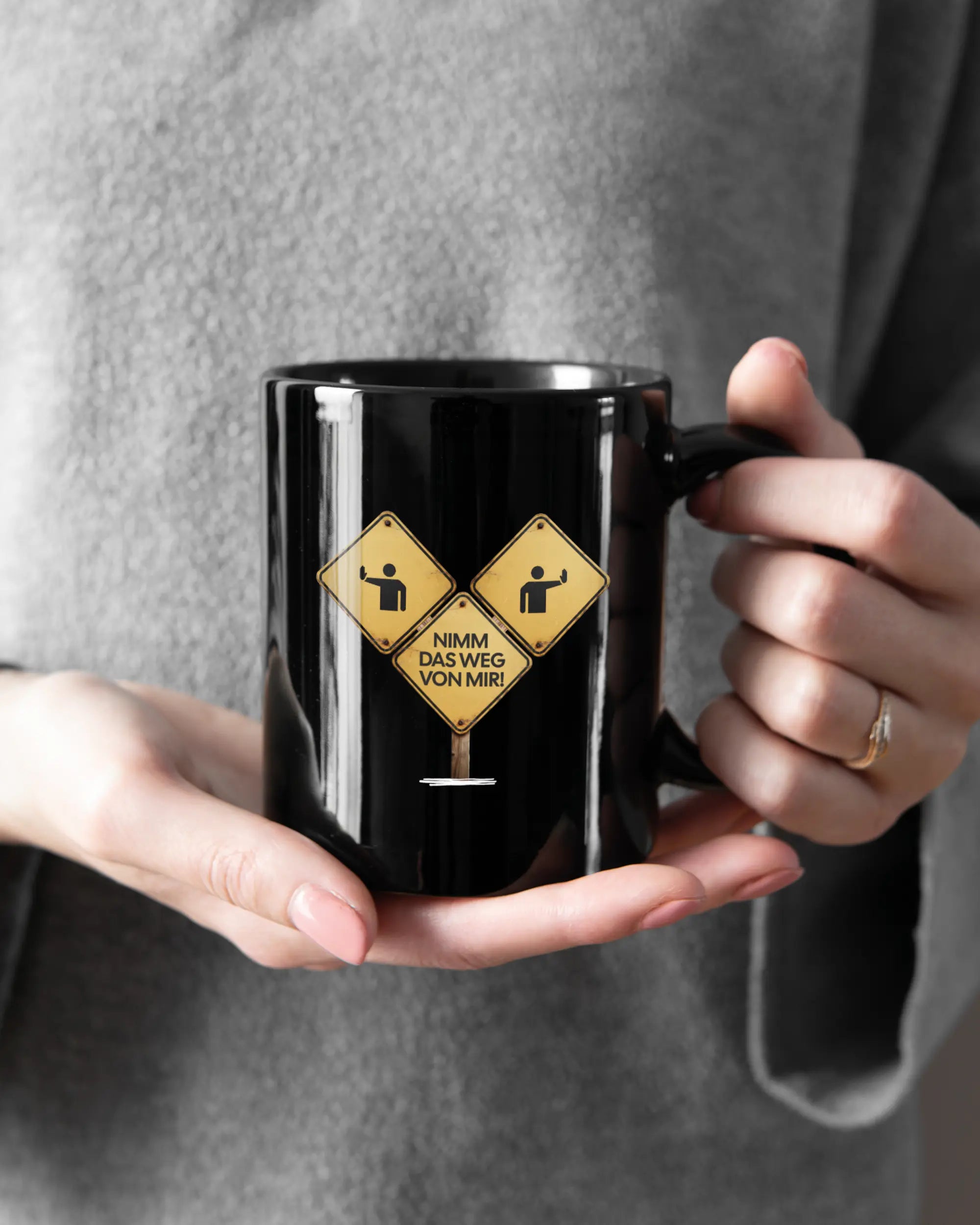 Rechte Seite der beidseitig bedruckten Keramiktasse von Maondo mit dem Design Schutzschild in der Farbe Black gehalten von Frauenhänden