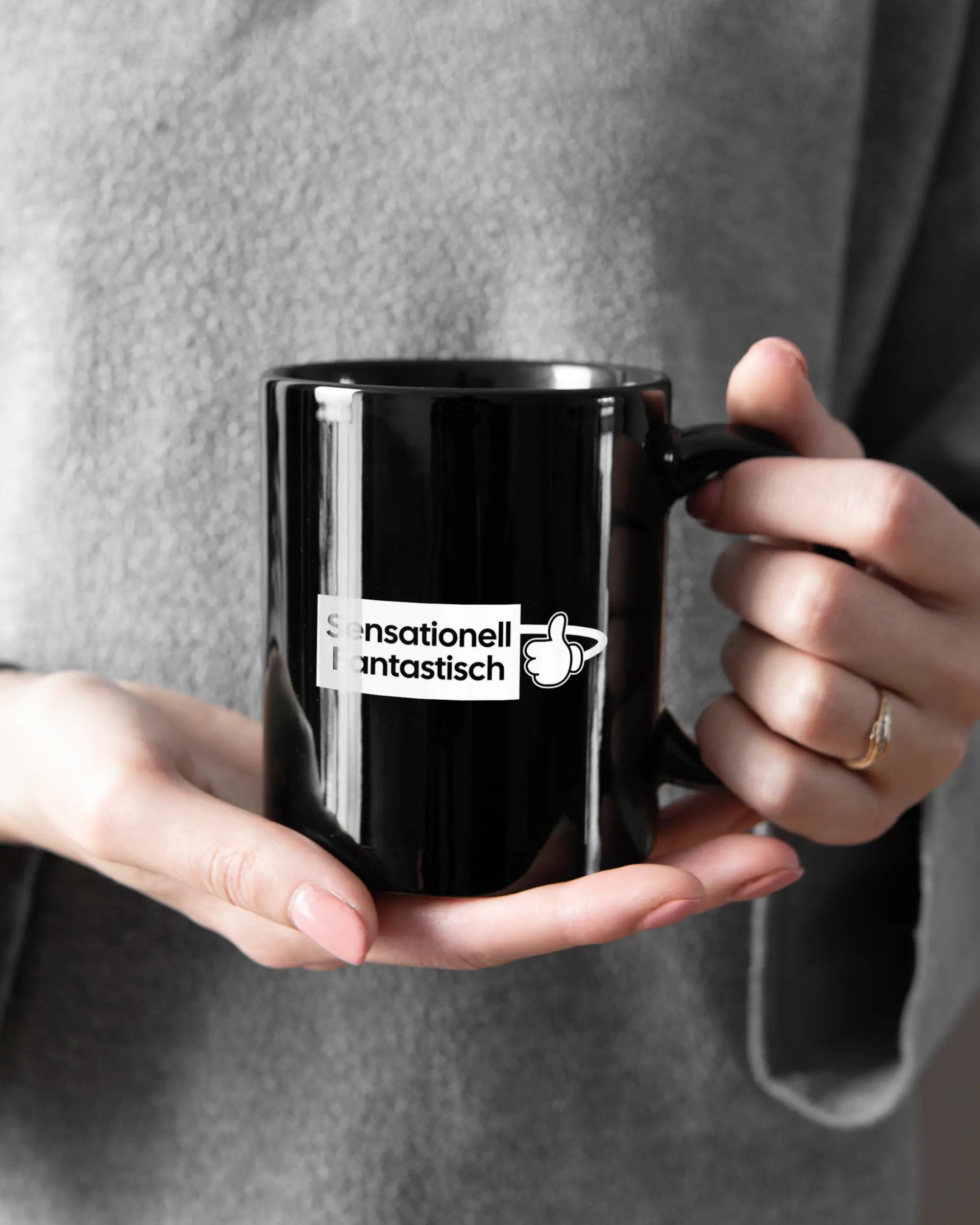 Rechte Seite der beidseitig bedruckten Keramiktasse von Maondo mit dem Design Fantastisch in der Farbe Black gehalten von Frauenhänden