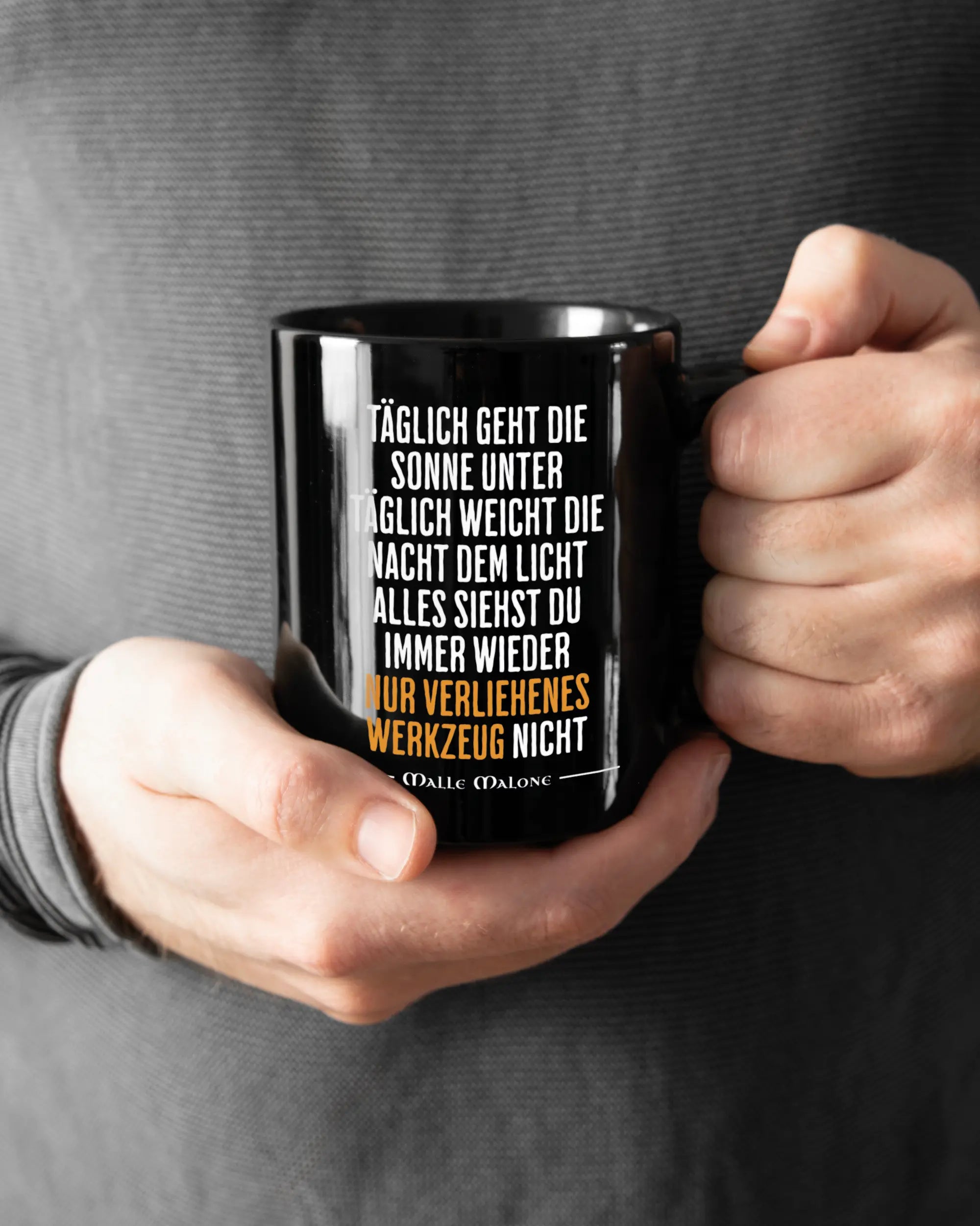 Rechte Seite der beidseitig bedruckten Keramiktasse von Maondo mit dem Design Wegzeug in der Farbe Black gehalten von Männerhänden