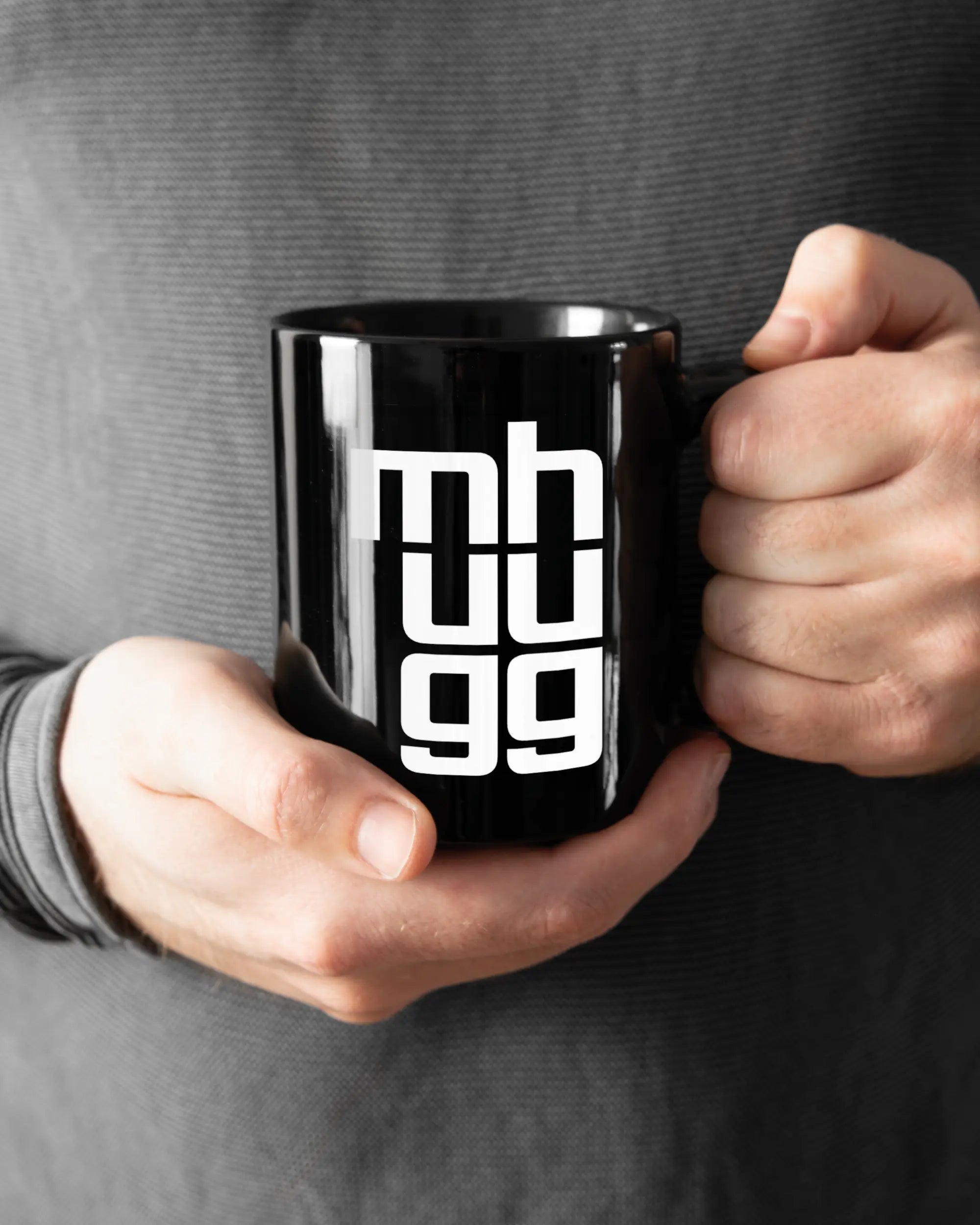 Rechte Seite der beidseitig bedruckten Keramiktasse von Maondo mit dem Design Hug Mug in der Farbe Black gehalten von Männerhänden