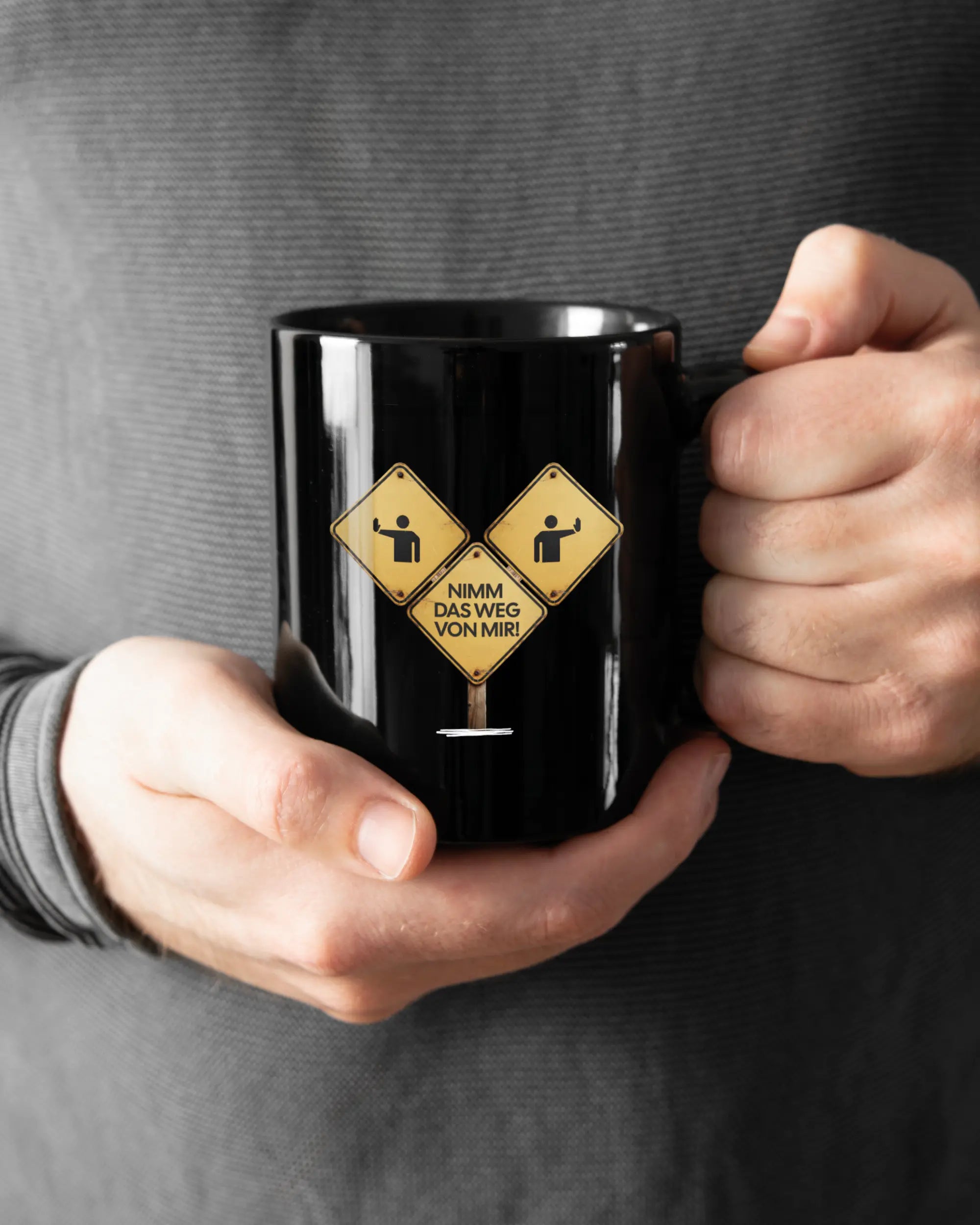 Rechte Seite der beidseitig bedruckten Keramiktasse von Maondo mit dem Design Schutzschild in der Farbe Black gehalten von Männerhänden
