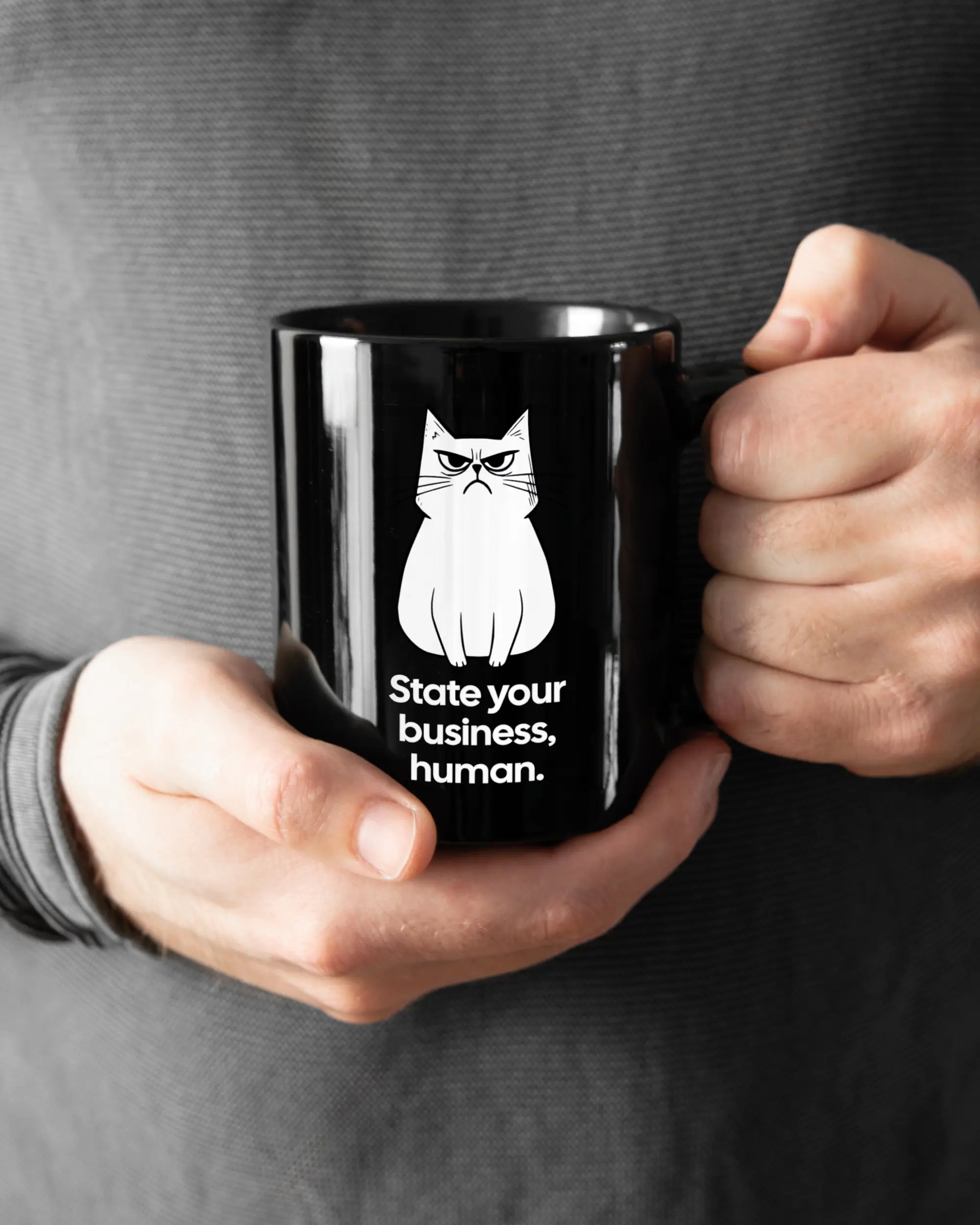 Rechte Seite der beidseitig bedruckten Keramiktasse von Maondo mit dem Design Grumpy Purr in der Farbe Black gehalten von Männerhänden