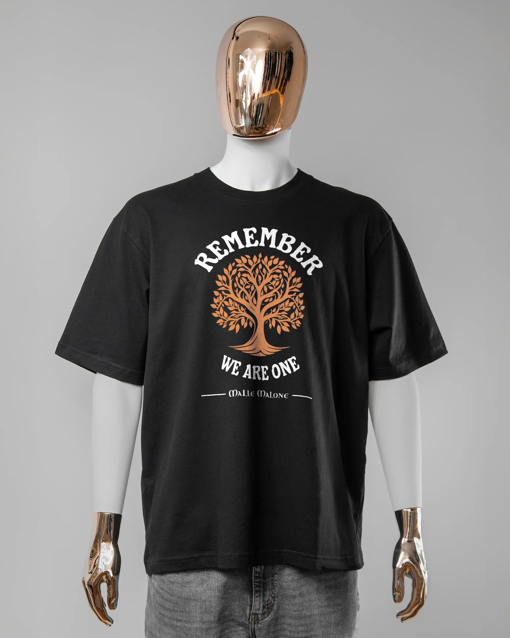 Vorderseite des Basic Unisex T-Shirt Oversized von Maondo mit dem Design We are one in der Farbe Black und in der Größe L getragen von einer maskulinen Puppe