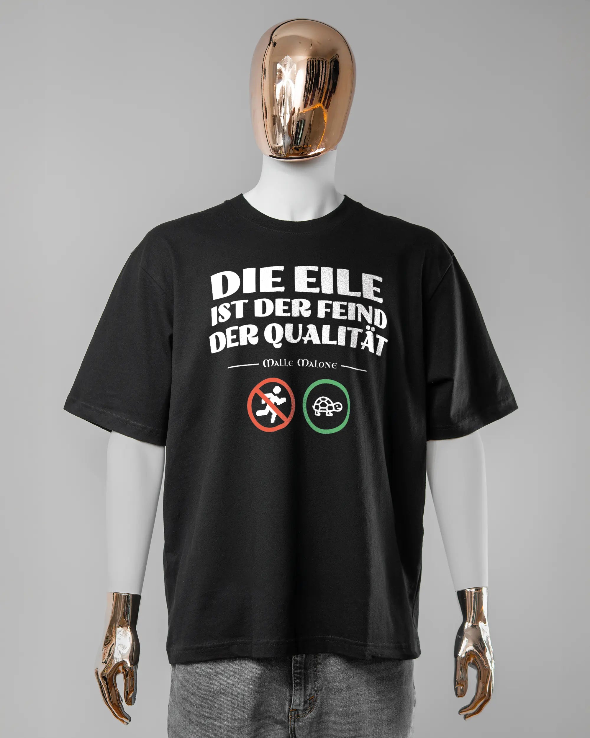 Vorderseite des Basic Unisex T-Shirt Oversized von Maondo mit dem Design Keine Eile in der Farbe Black und in der Größe L getragen von einer maskulinen Puppe