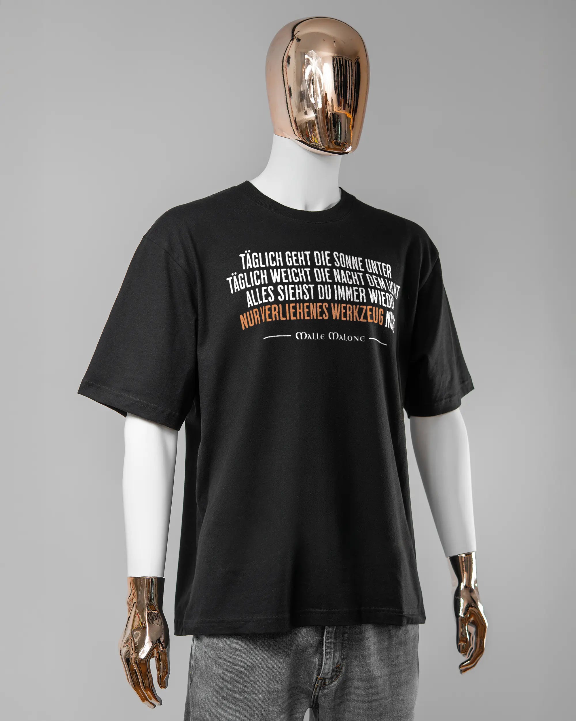 Vorderseite des Basic Unisex T-Shirt Oversized von Maondo mit dem Design Wegzeug in der Farbe Black und in der Größe L getragen von einer maskulinen Puppe