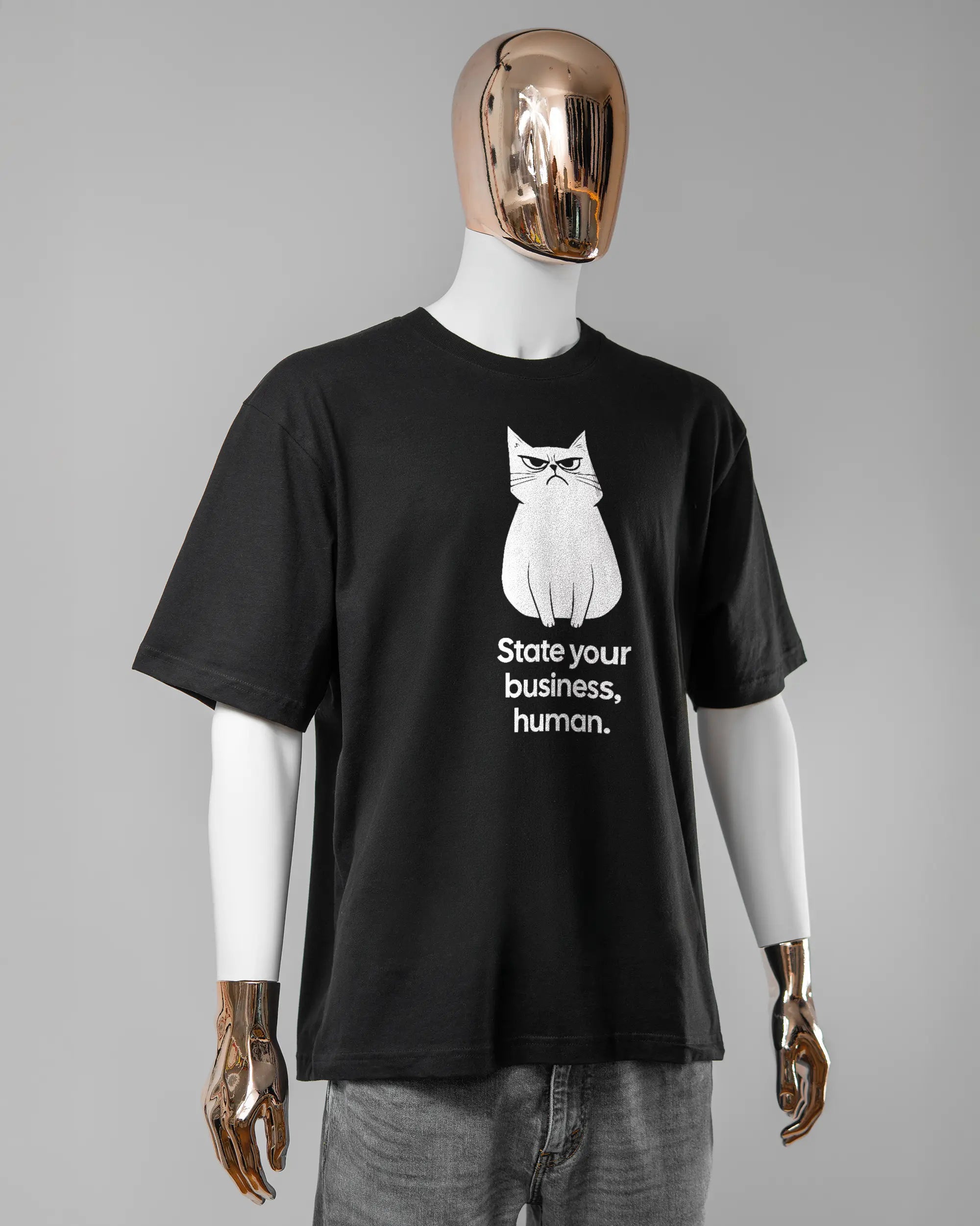 Vorderseite des Basic Unisex T-Shirt Oversized von Maondo mit dem Design Grumpy Purr in der Farbe Black und in der Größe L getragen von einer maskulinen Puppe
