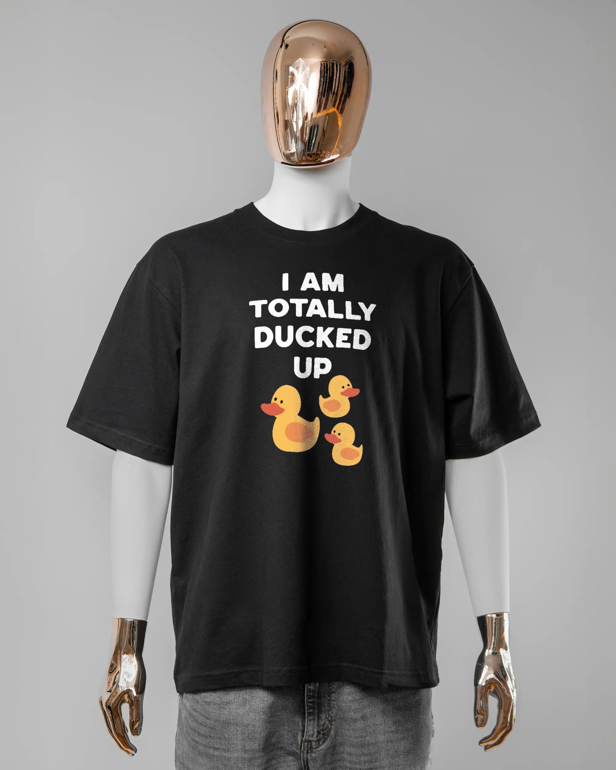 Vorderseite des Basic Unisex T-Shirt Oversized von Maondo mit dem Design Ducked Up in der Farbe Black und in der Größe L getragen von einer maskulinen Puppe