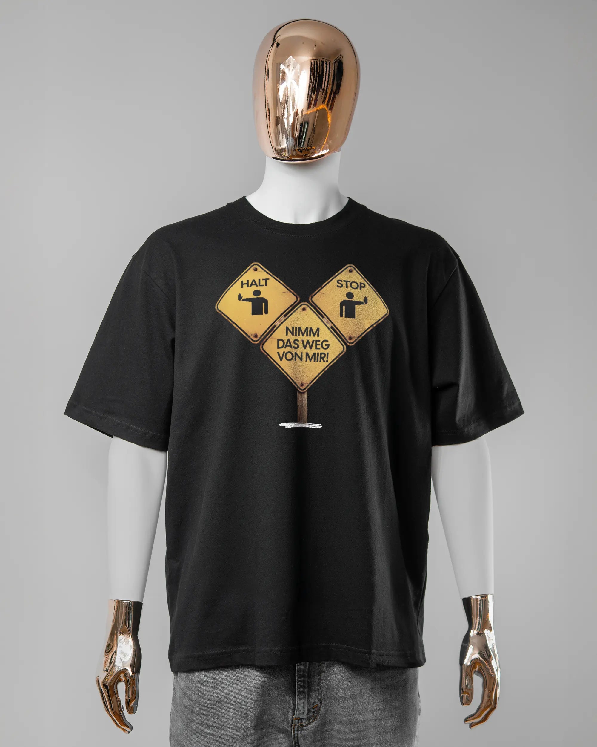 Vorderseite des Basic Unisex T-Shirt Oversized von Maondo mit dem Design Schutzschild in der Farbe Black und in der Größe L getragen von einer maskulinen Puppe