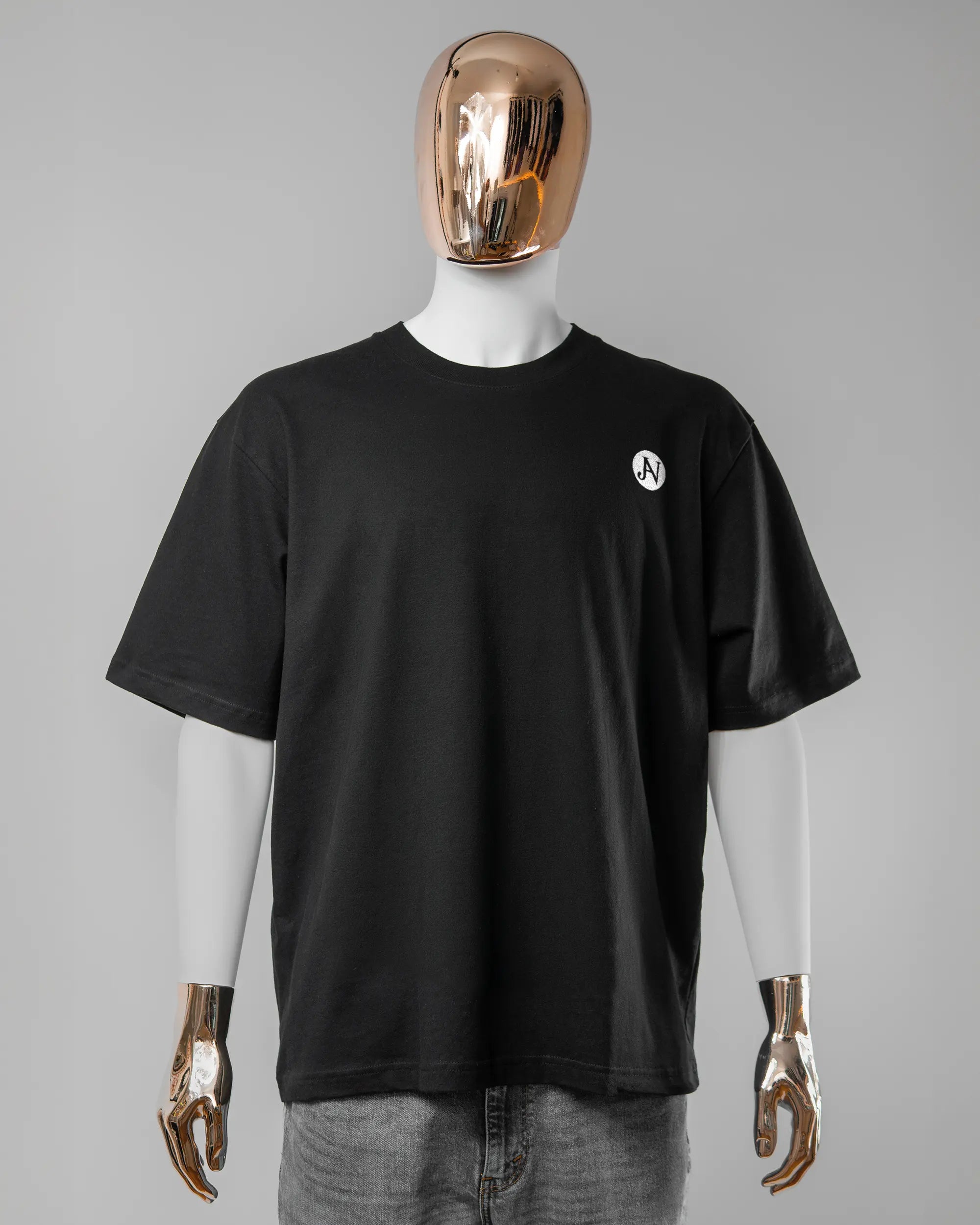 Vorderseite des Basic Unisex T-Shirt Oversized von Maondo mit dem Design JB1 in der Farbe Black und in der Größe L getragen von einer maskulinen Puppe