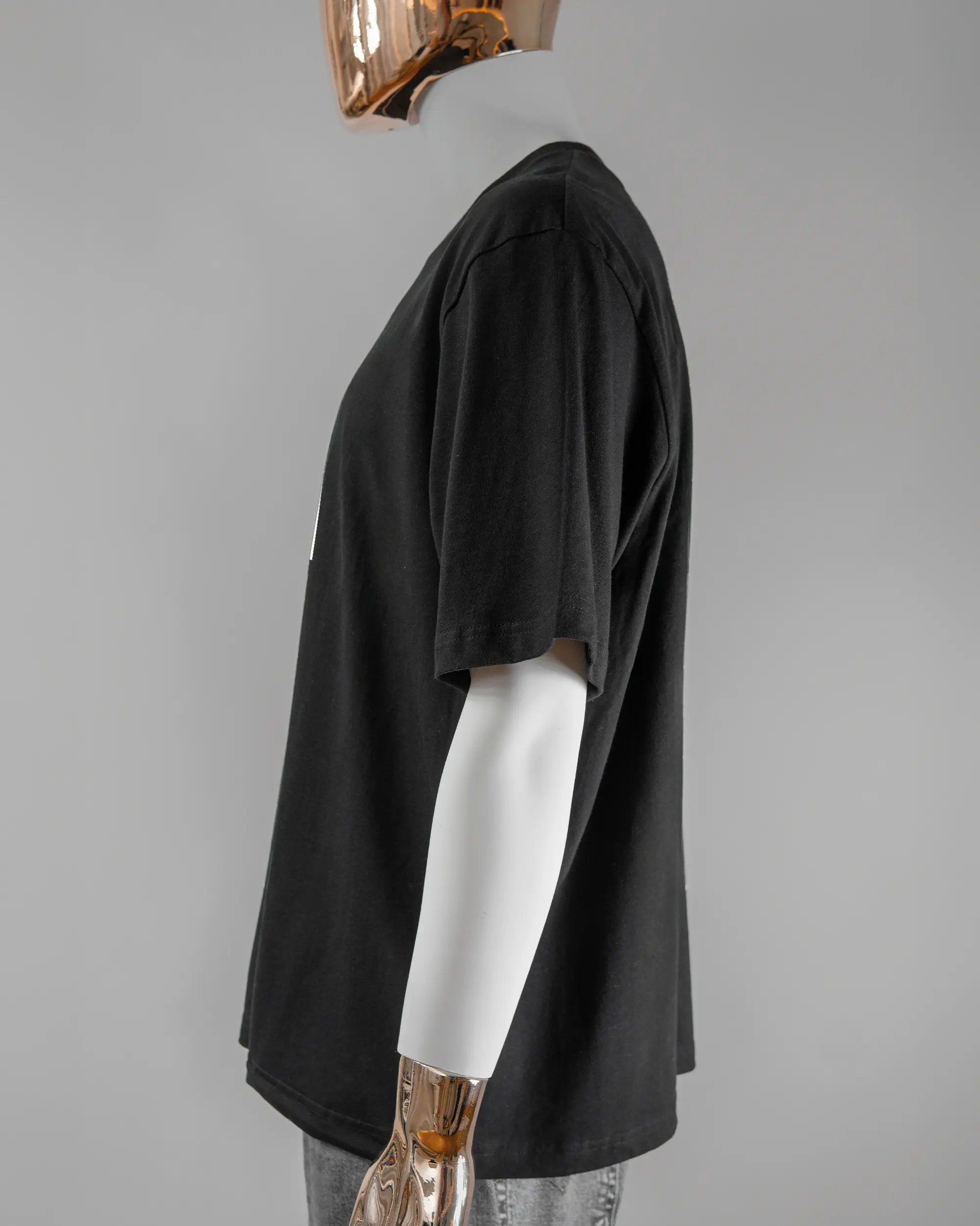 Seitenansicht des Basic Unisex T-Shirt Oversized von Maondo mit dem Design Puny Human vorne in der Farbe Black und in der Größe L getragen von einer maskulinen Puppe