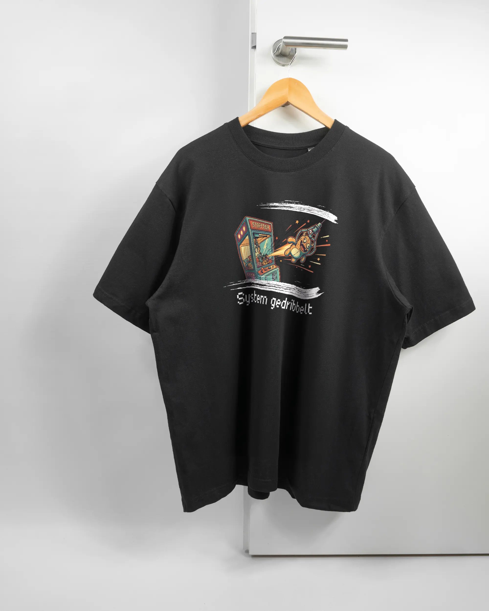 Vorderseite des Basic Unisex T-Shirt Oversized von Maondo mit dem Design System gedribbelt in der Farbe Black und in der Größe L auf einem Bügel an der Türklinke aufgehängt