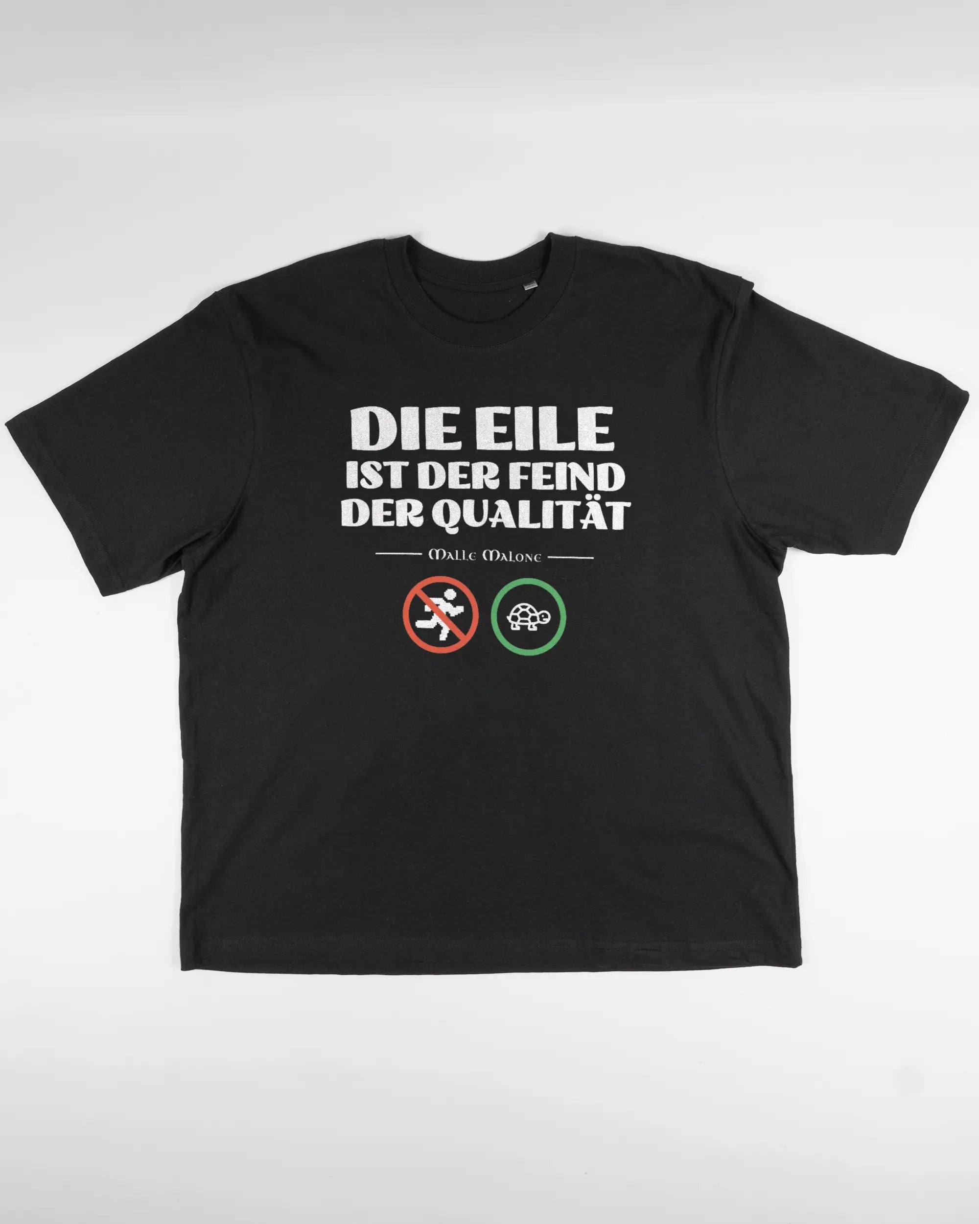 Vorderseite des Basic Unisex T-Shirt Oversized von Maondo mit dem Design Keine Eile in der Farbe Black und in der Größe L flach auf den Boden gelegt