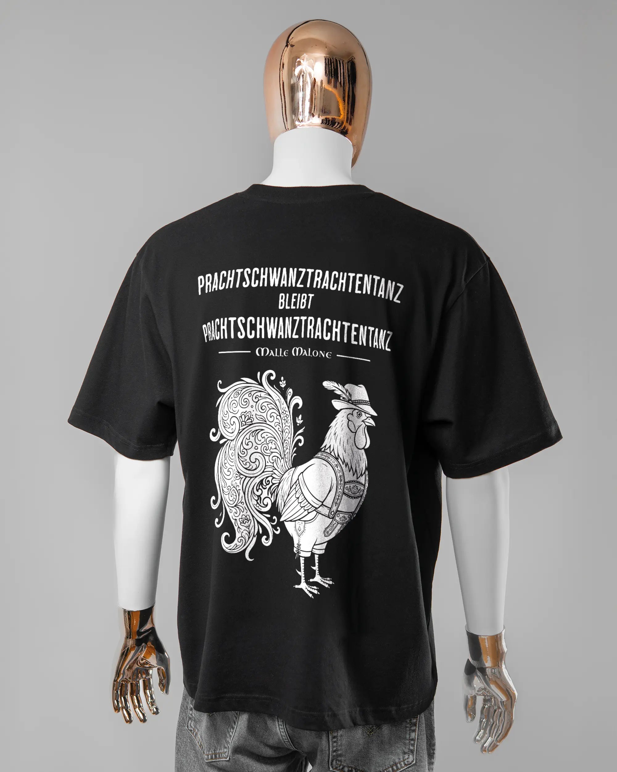 Rückseite des Basic Unisex T-Shirt Oversized von Maondo mit dem Design Trachtentanz in der Farbe Black und in der Größe L getragen von einer maskulinen Puppe
