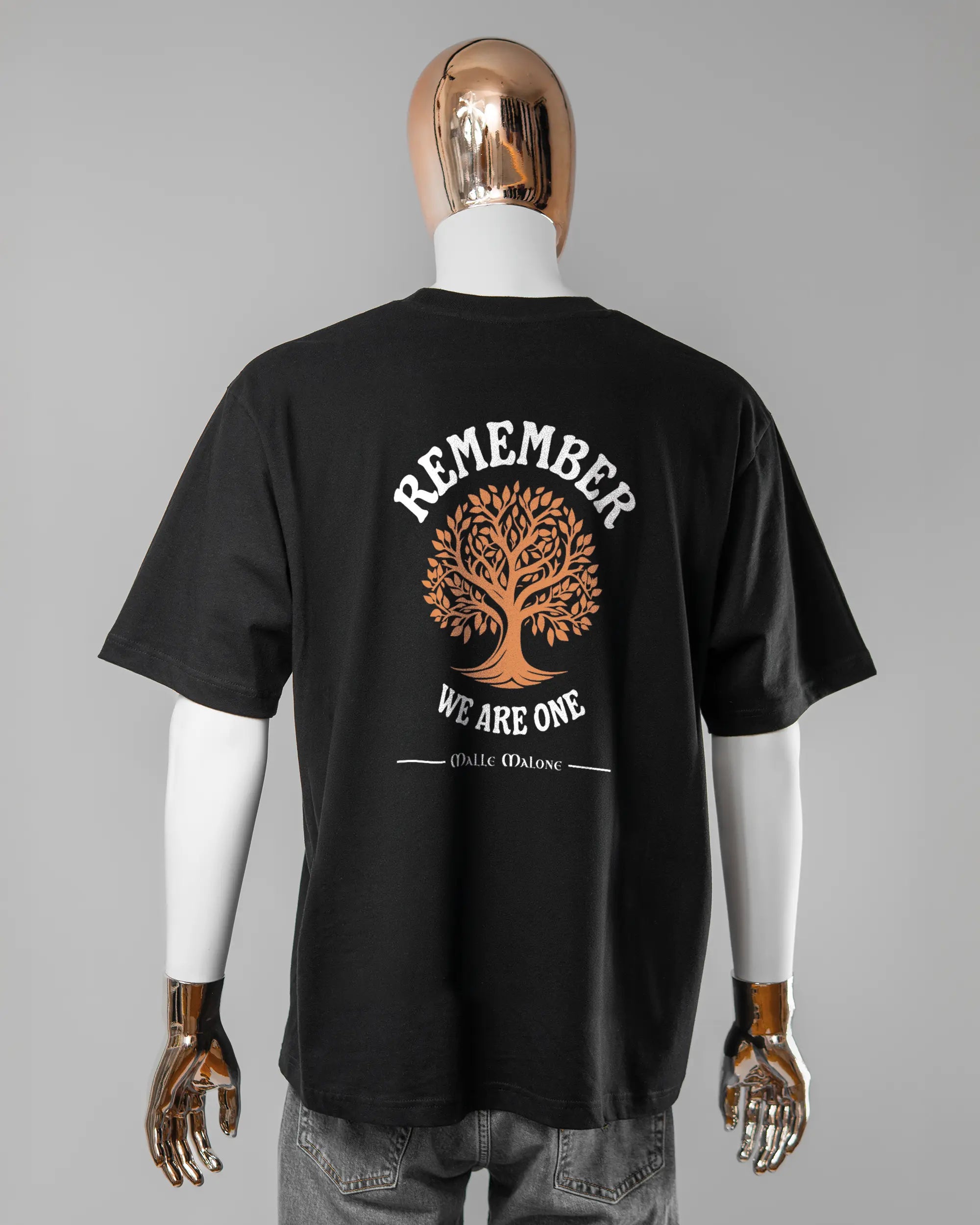 Rückseite des Basic Unisex T-Shirt Oversized von Maondo mit dem Design We are one in der Farbe Black und in der Größe L getragen von einer maskulinen Puppe