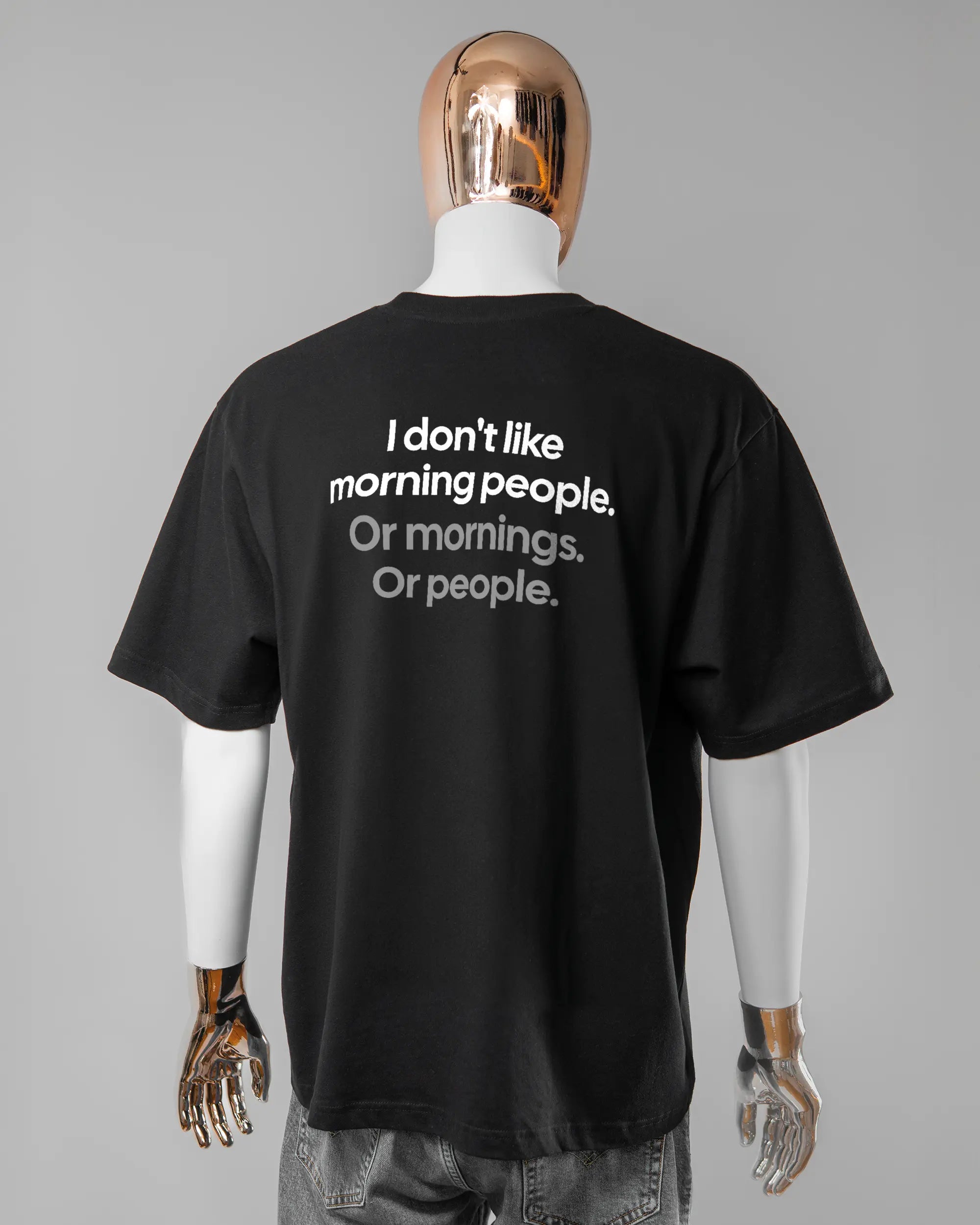 Rückseite des Basic Unisex T-Shirt Oversized von Maondo mit dem Design Morning Person in der Farbe Black und in der Größe L getragen von einer maskulinen Puppe