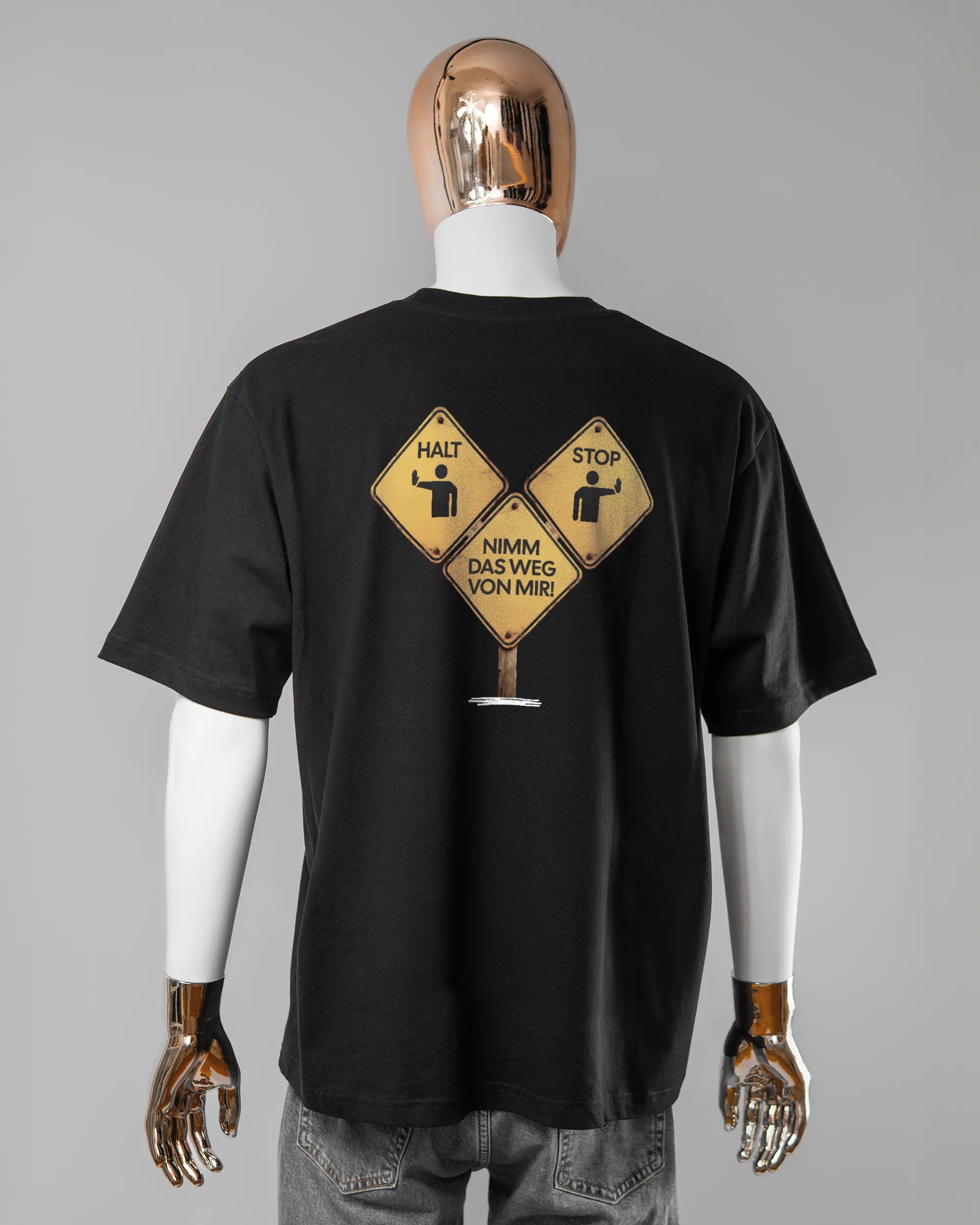 Rückseite des Basic Unisex T-Shirt Oversized von Maondo mit dem Design Schutzschild in der Farbe Black und in der Größe L getragen von einer maskulinen Puppe