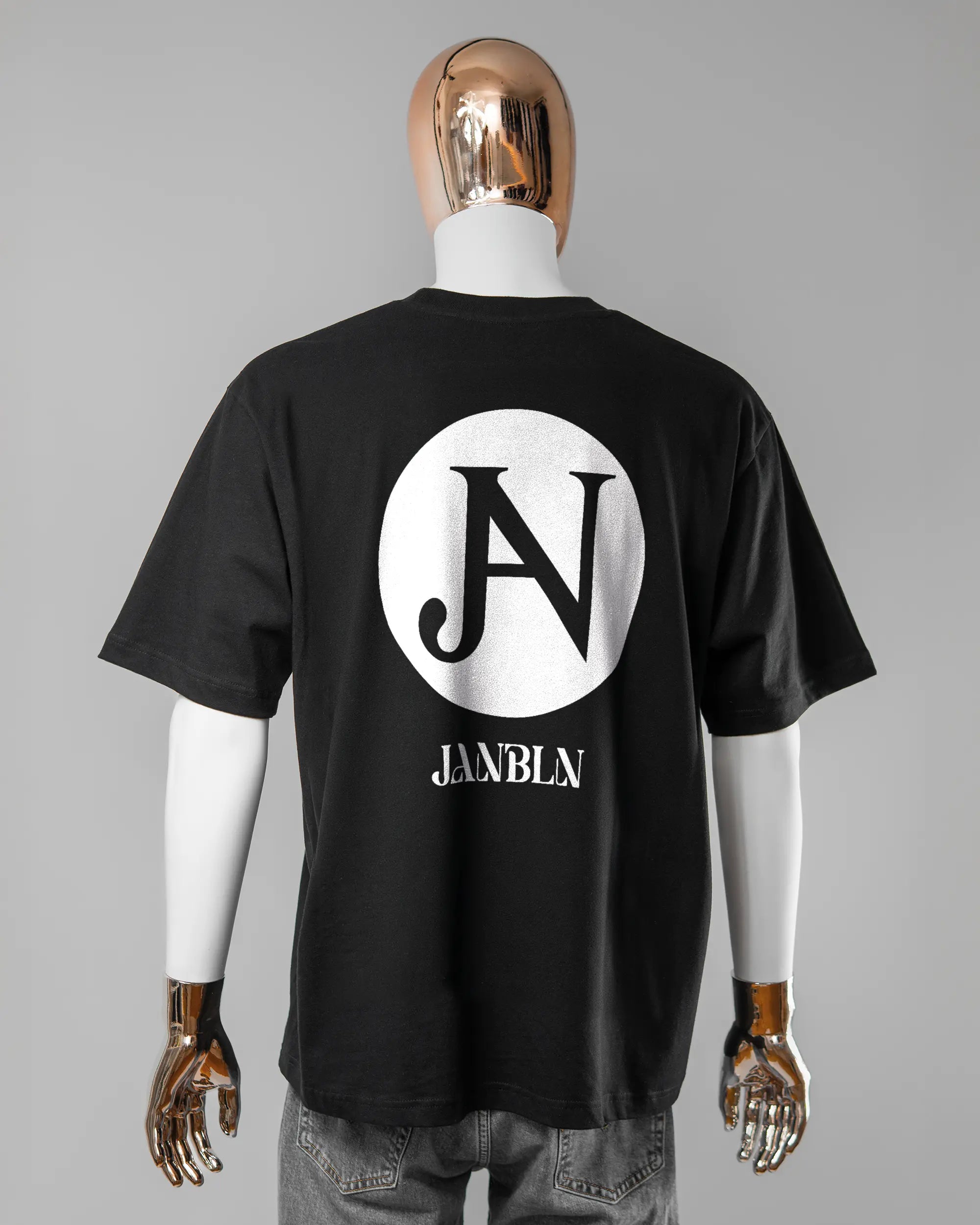 Rückseite des Basic Unisex T-Shirt Oversized von Maondo mit dem Design JB1 in der Farbe Black und in der Größe L getragen von einer maskulinen Puppe