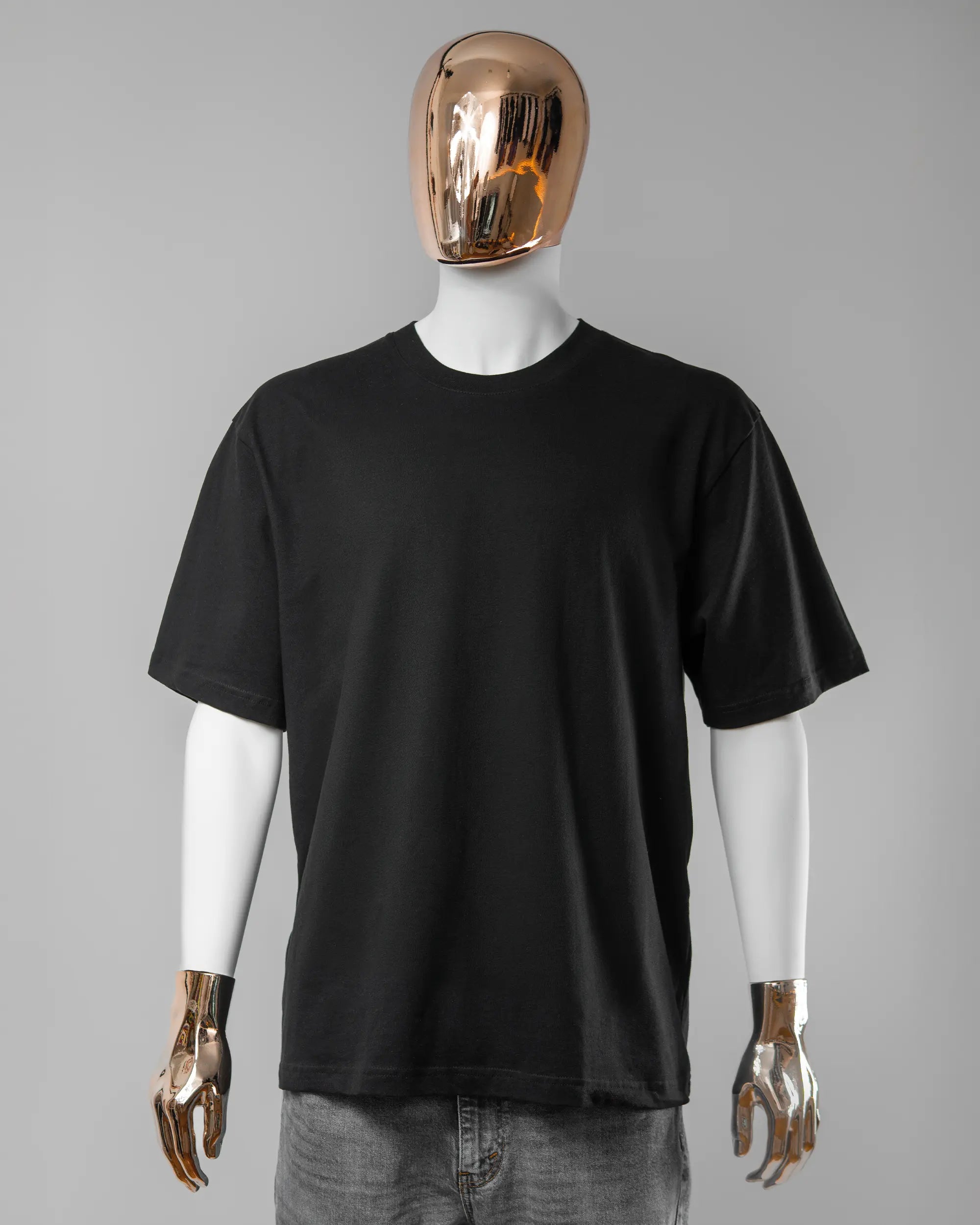 Vorderseite des Basic Unisex T-Shirt Oversized von Maondo ohne Motiv in der Farbe Black und in der Größe L getragen von einer maskulinen Puppe