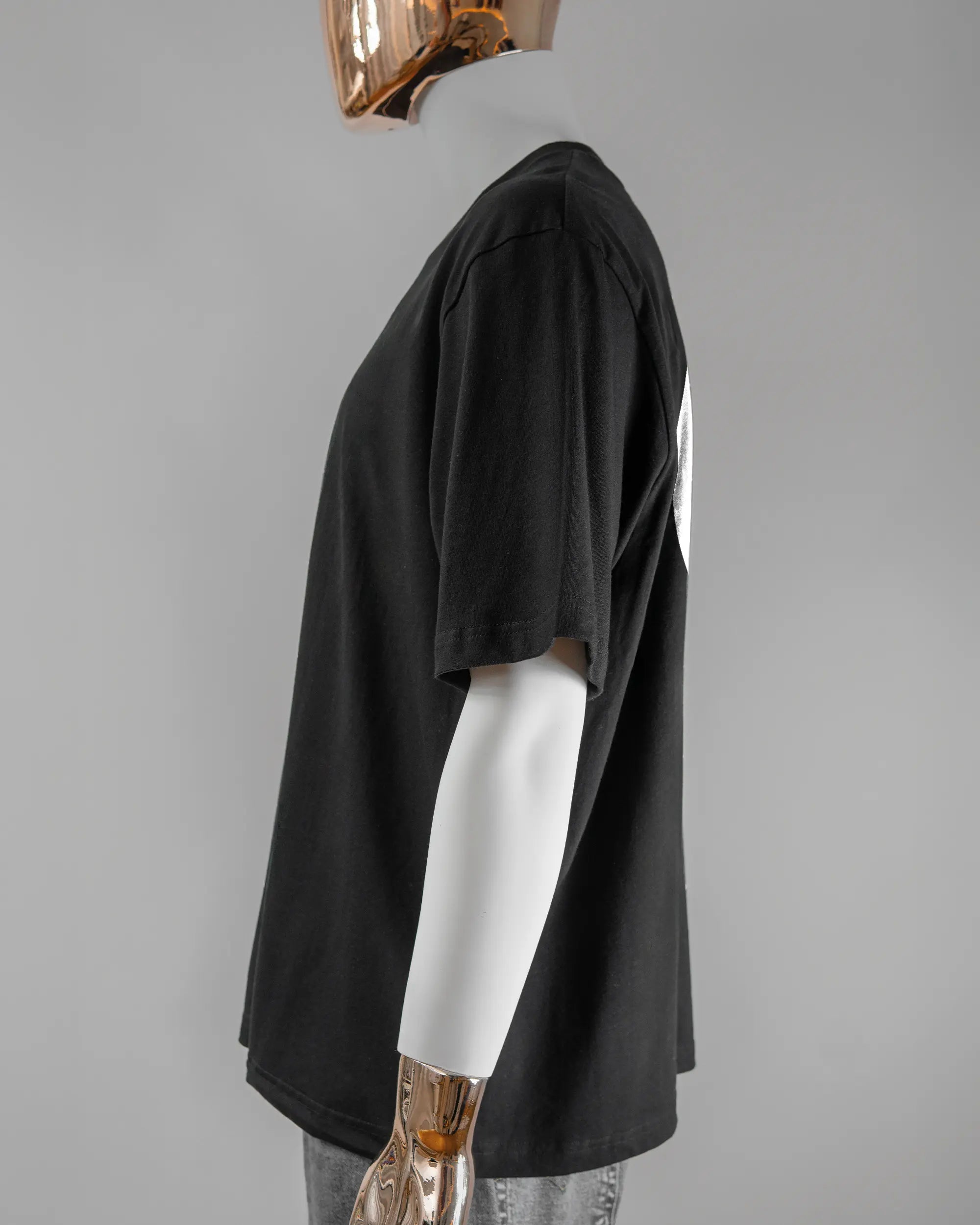 Seitenansicht des Basic Unisex T-Shirt Oversized von Maondo mit dem Design JB1 hinten in der Farbe Black und in der Größe L getragen von einer maskulinen Puppe