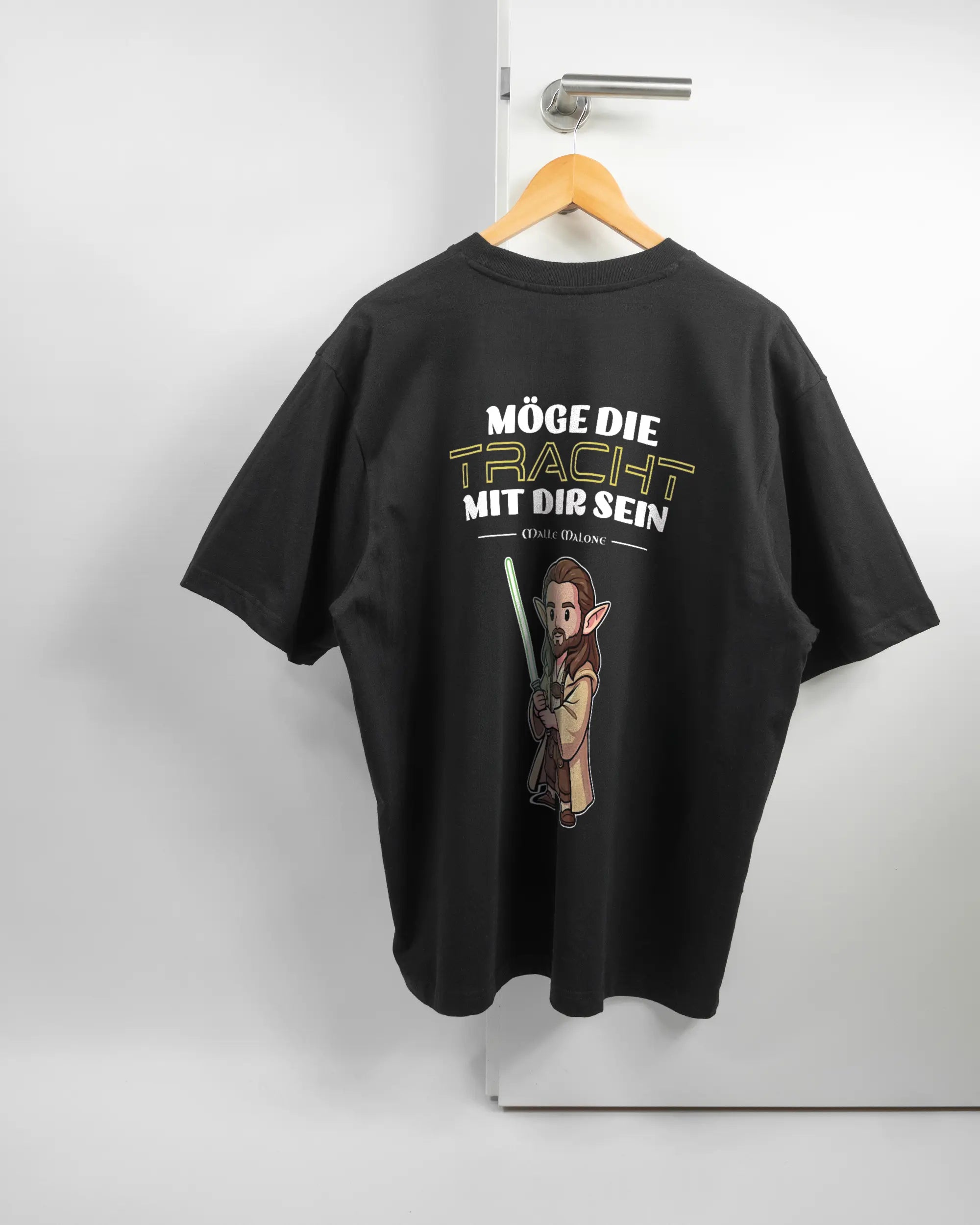 Rückseite des Basic Unisex T-Shirt Oversized von Maondo mit dem Design Tracht mit dir in der Farbe Black und in der Größe L auf einem Bügel an der Türklinke aufgehängt