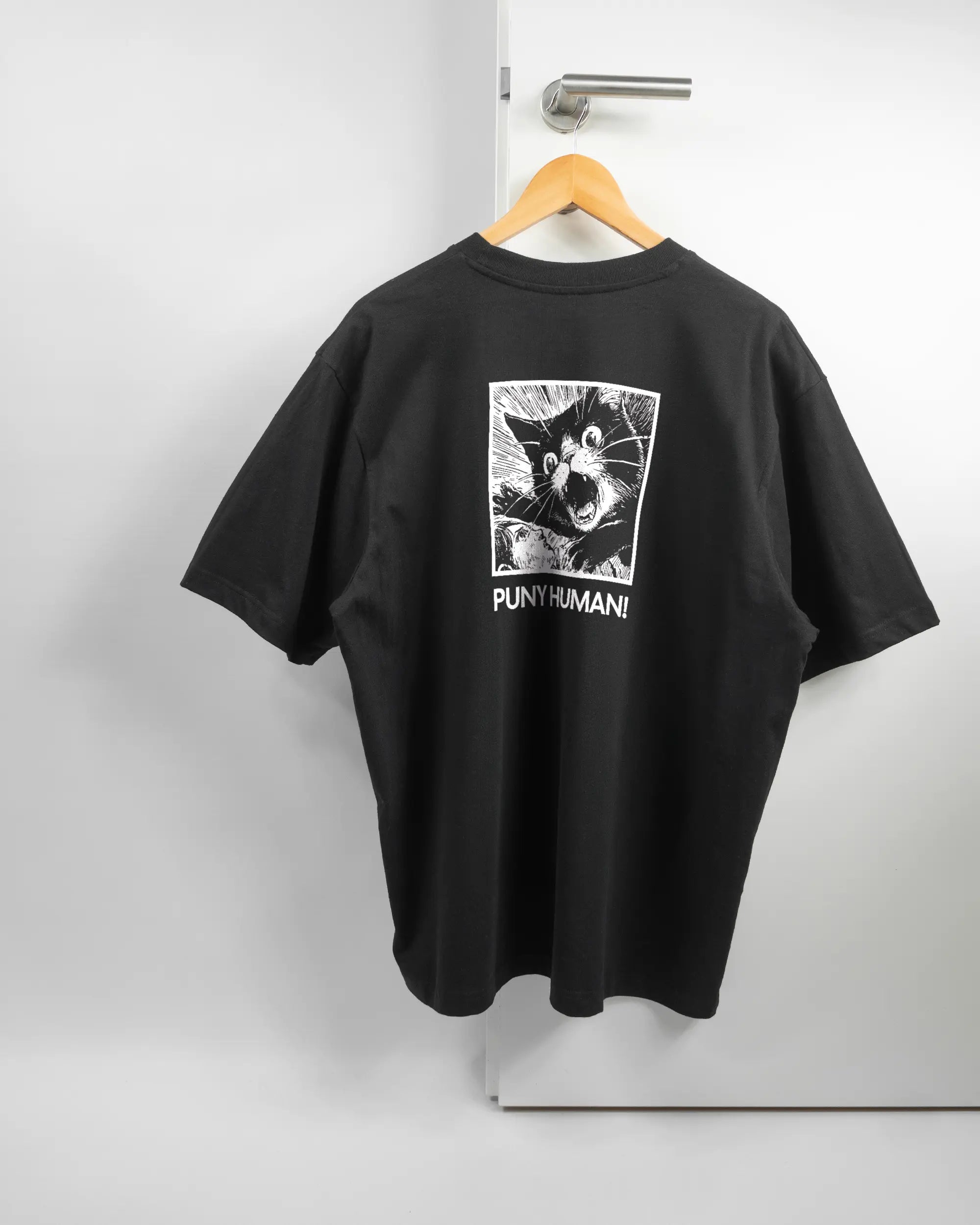 Rückseite des Basic Unisex T-Shirt Oversized von Maondo mit dem Design Puny Human in der Farbe Black und in der Größe L auf einem Bügel an der Türklinke aufgehängt