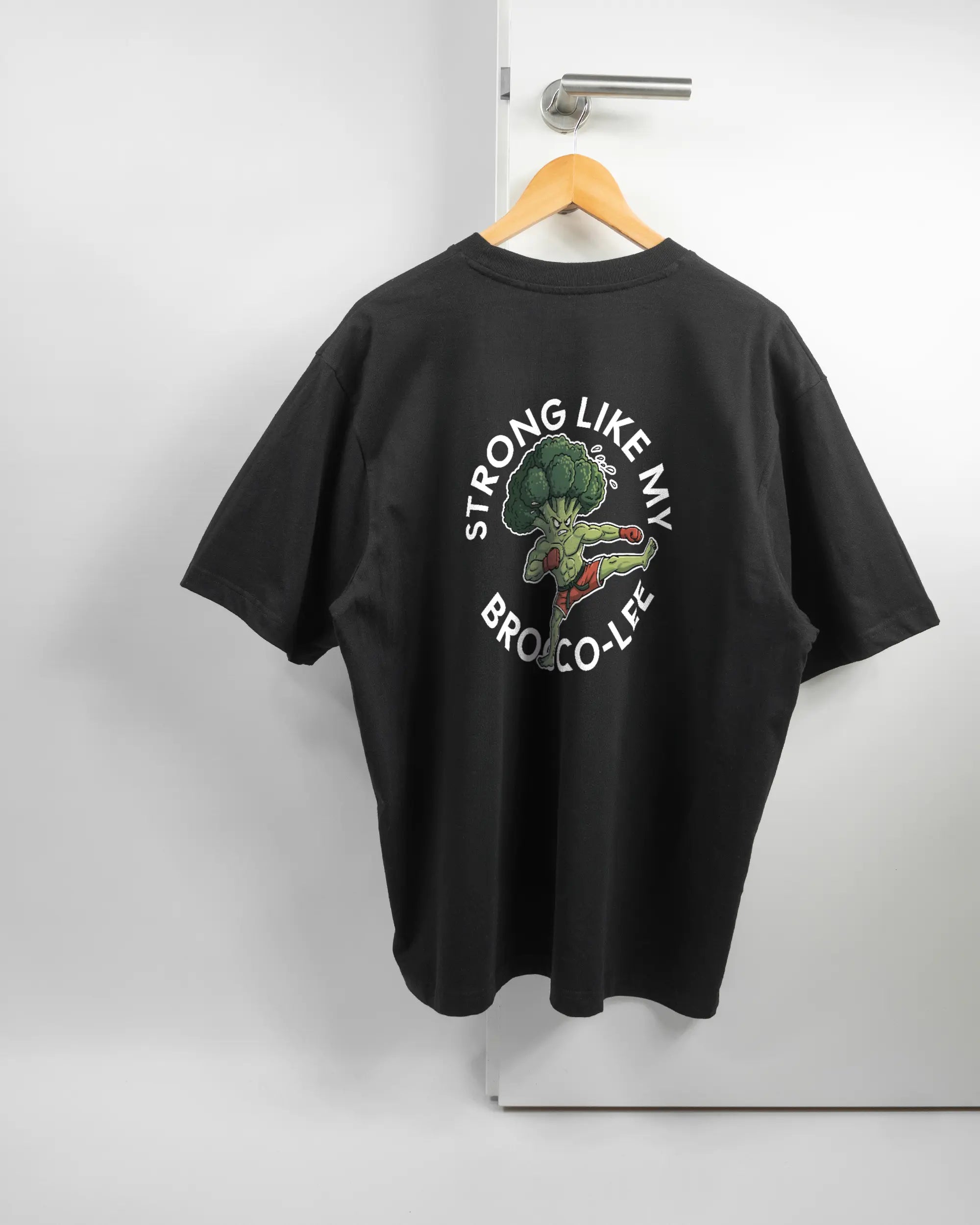 Rückseite des Basic Unisex T-Shirt Oversized von Maondo mit dem Design Brocco-Lee in der Farbe Black und in der Größe L auf einem Bügel an der Türklinke aufgehängt