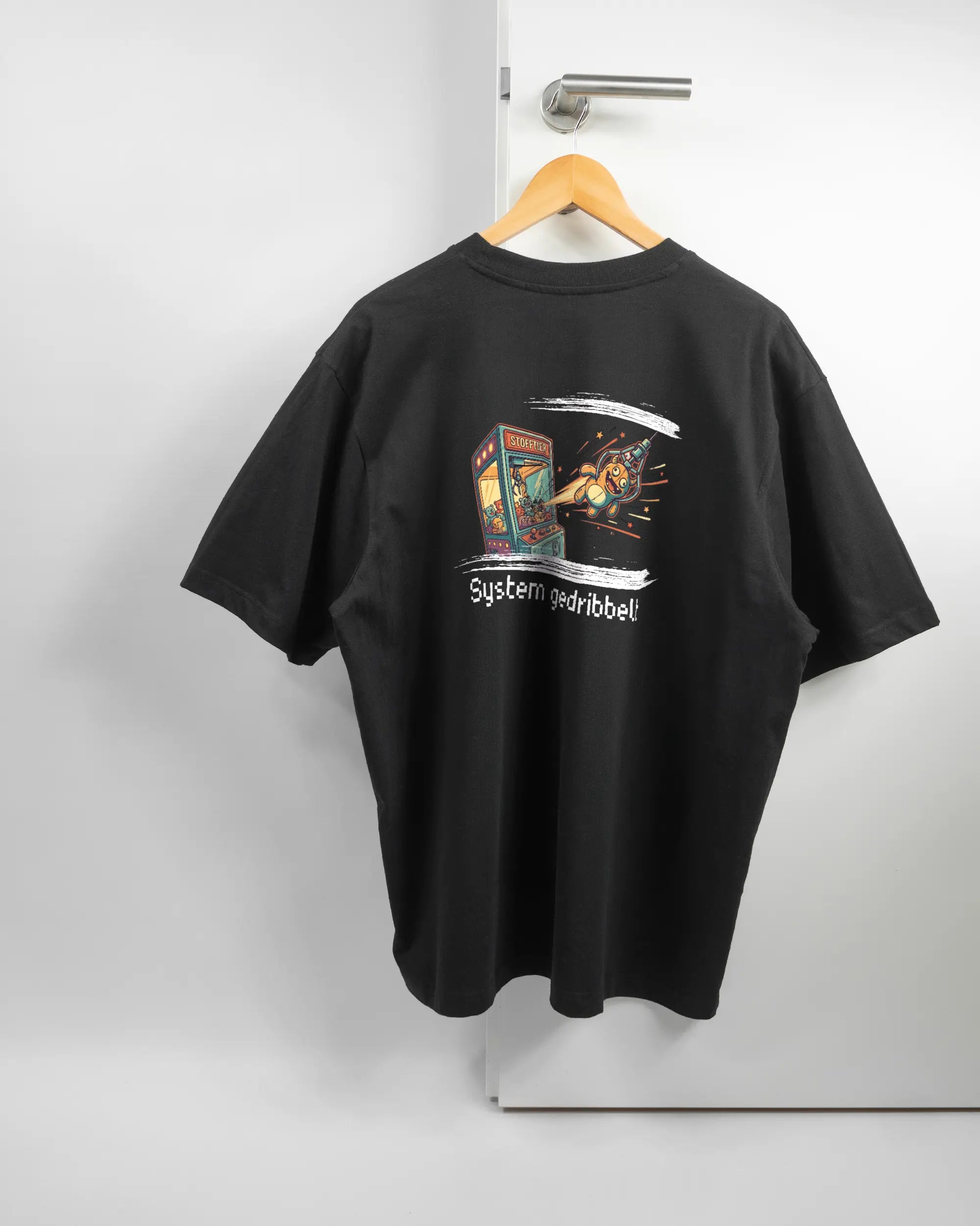 Rückseite des Basic Unisex T-Shirt Oversized von Maondo mit dem Design System gedribbelt in der Farbe Black und in der Größe L auf einem Bügel an der Türklinke aufgehängt