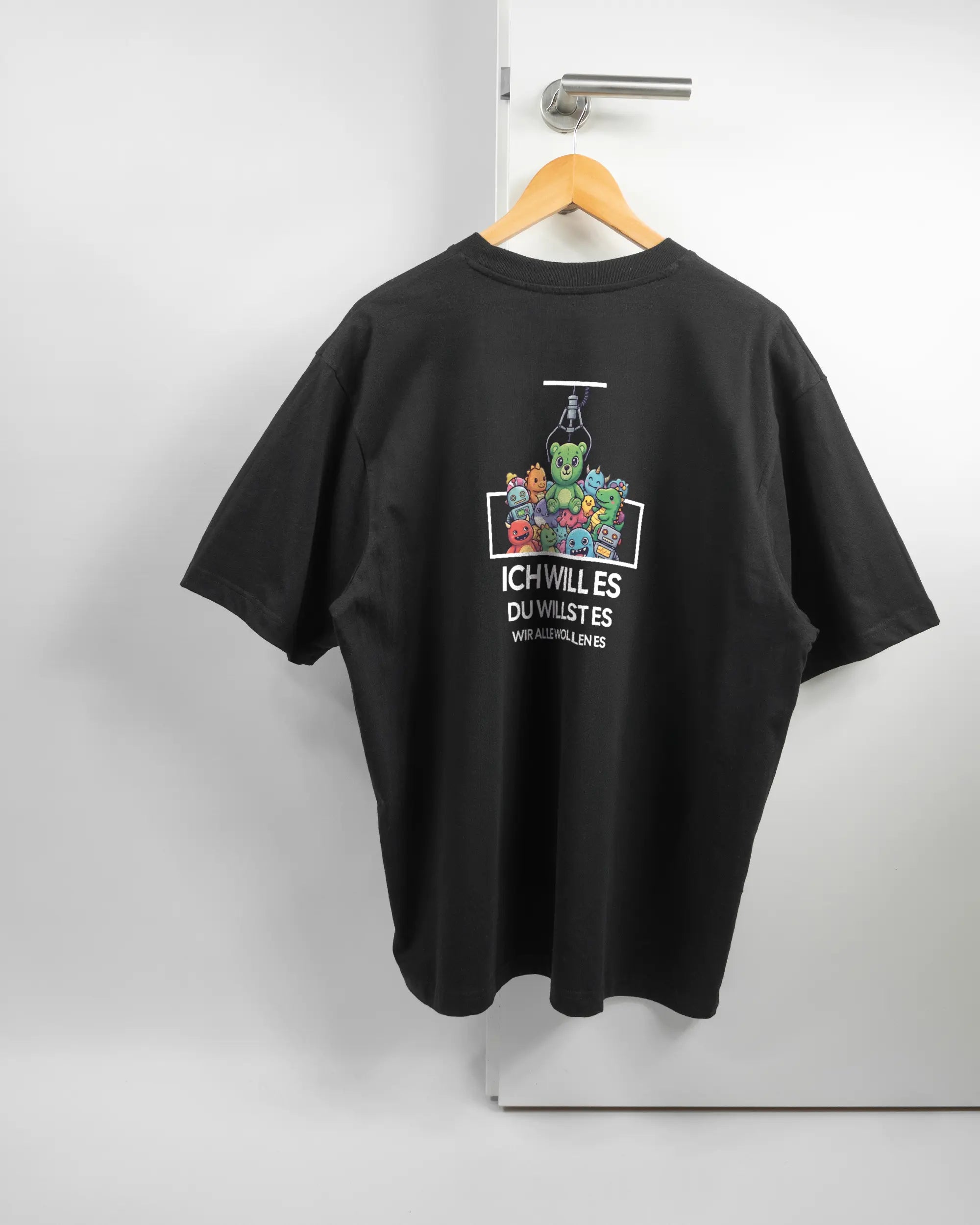 Rückseite des Basic Unisex T-Shirt Oversized von Maondo mit dem Design Will Stofftier in der Farbe Black und in der Größe L auf einem Bügel an der Türklinke aufgehängt