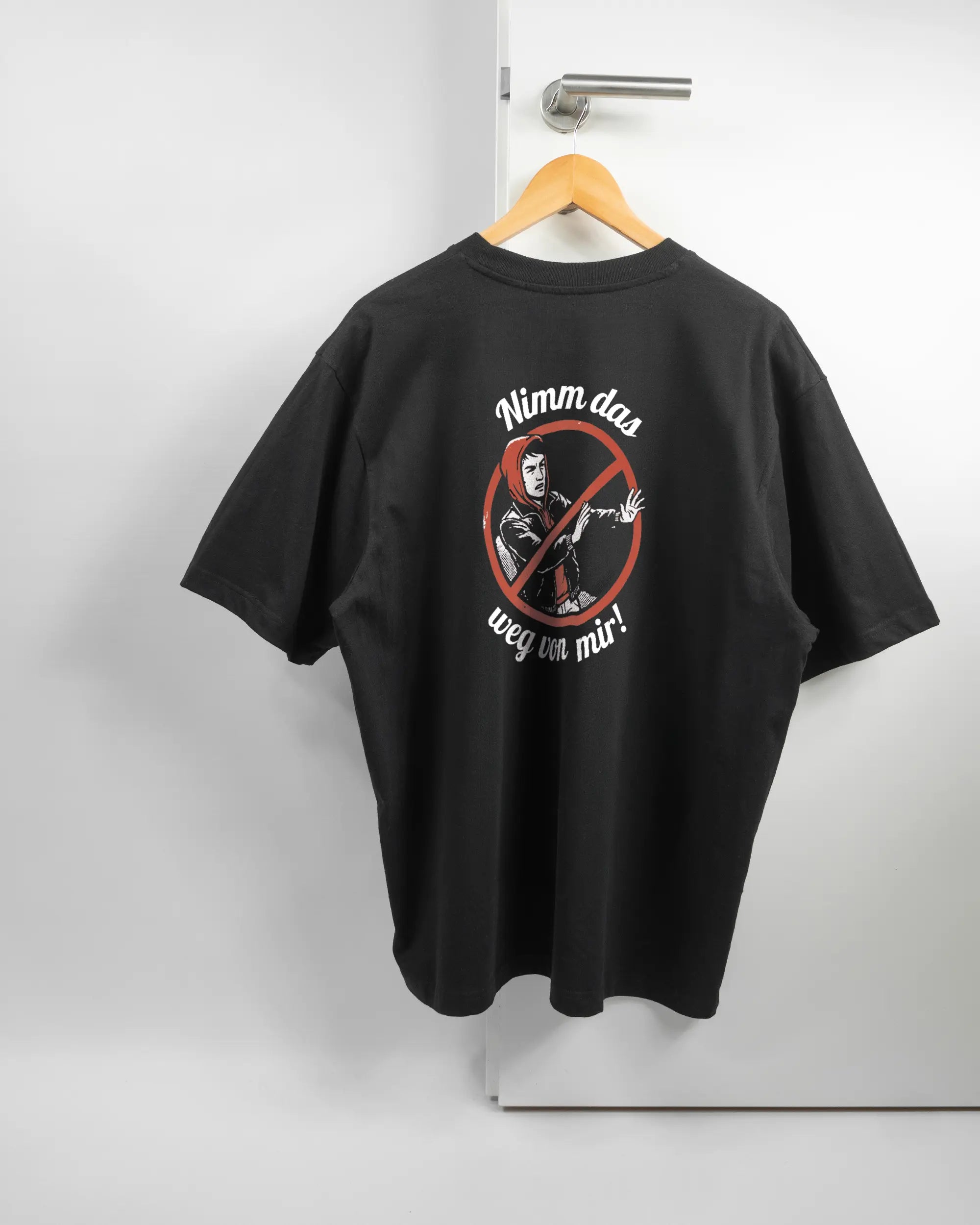 Rückseite des Basic Unisex T-Shirt Oversized von Maondo mit dem Design Nimm das weg in der Farbe Black und in der Größe L auf einem Bügel an der Türklinke aufgehängt