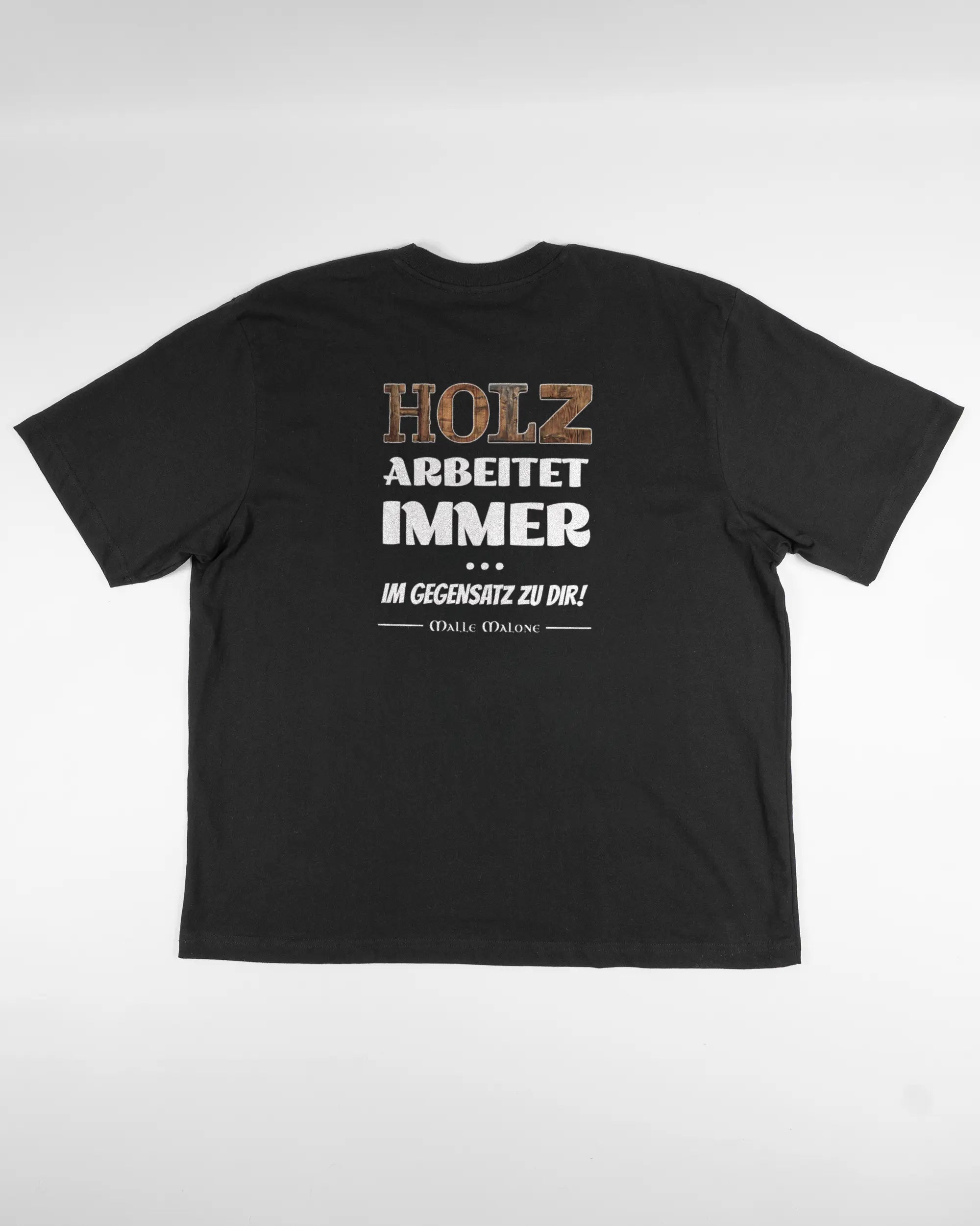 Rückseite des Basic Unisex T-Shirt Oversized von Maondo mit dem Design Holzarbeit in der Farbe Black und in der Größe L flach auf den Boden gelegt
