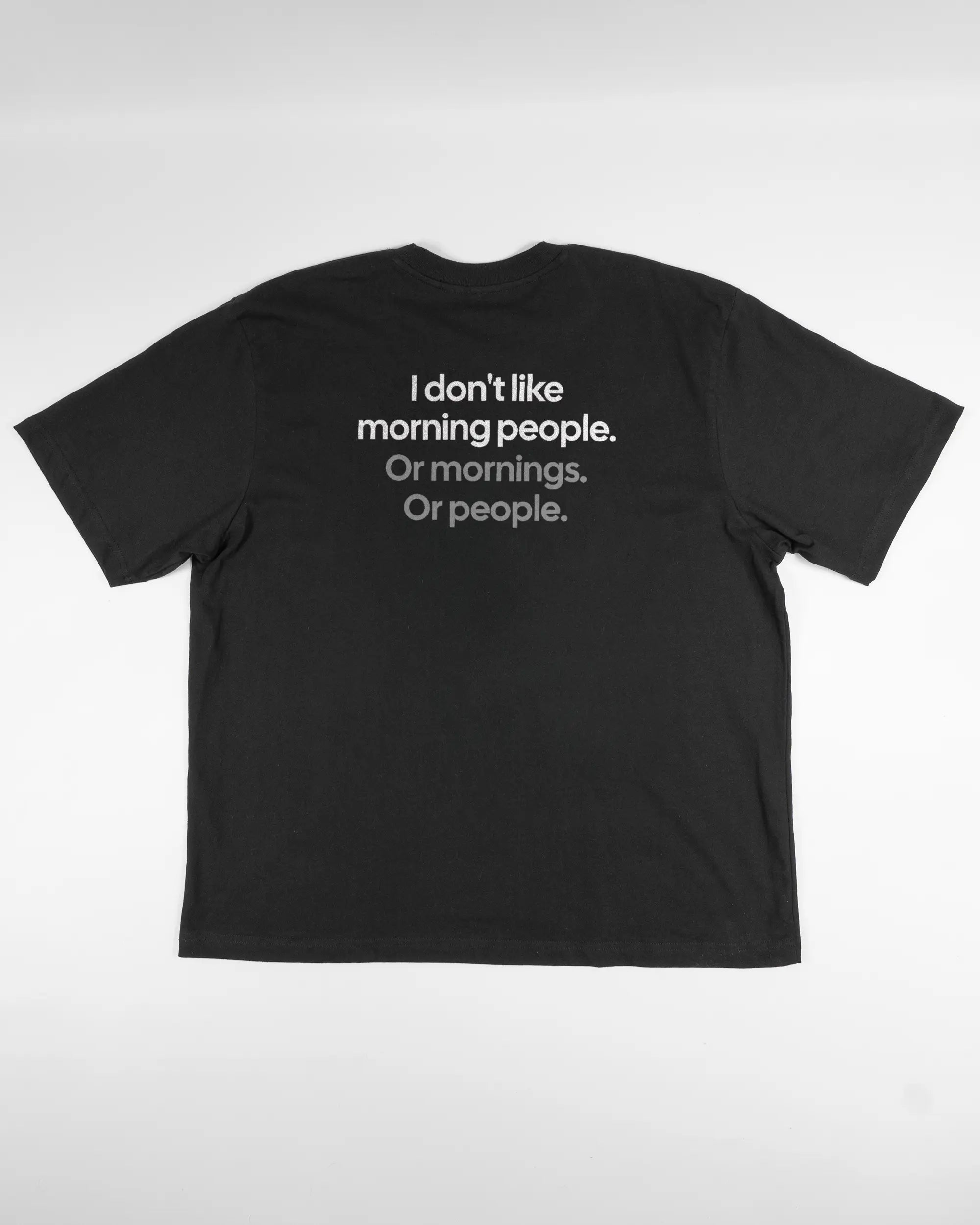 Rückseite des Basic Unisex T-Shirt Oversized von Maondo mit dem Design Morning Person in der Farbe Black und in der Größe L flach auf den Boden gelegt