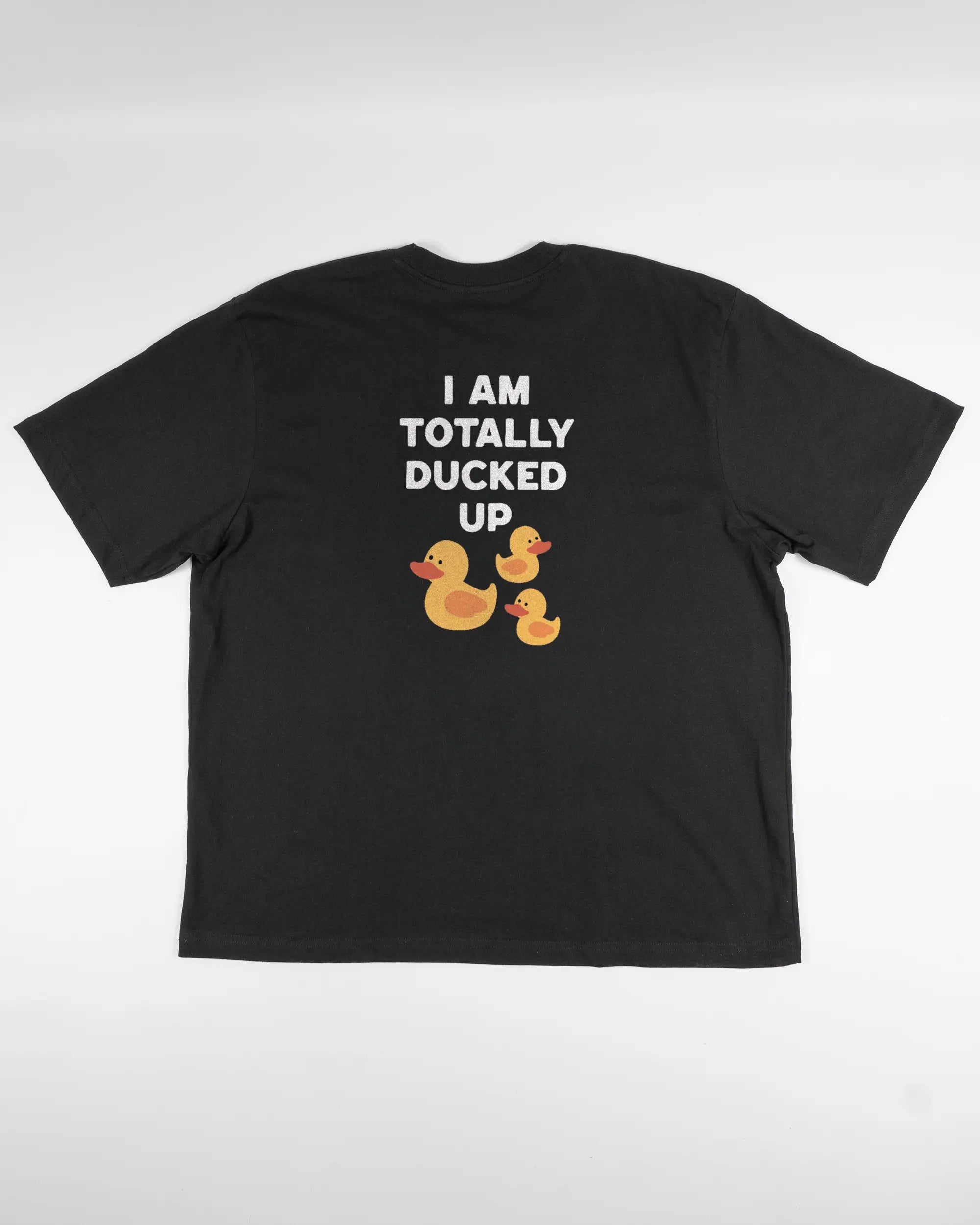 Rückseite des Basic Unisex T-Shirt Oversized von Maondo mit dem Design Ducked Up in der Farbe Black und in der Größe L flach auf den Boden gelegt